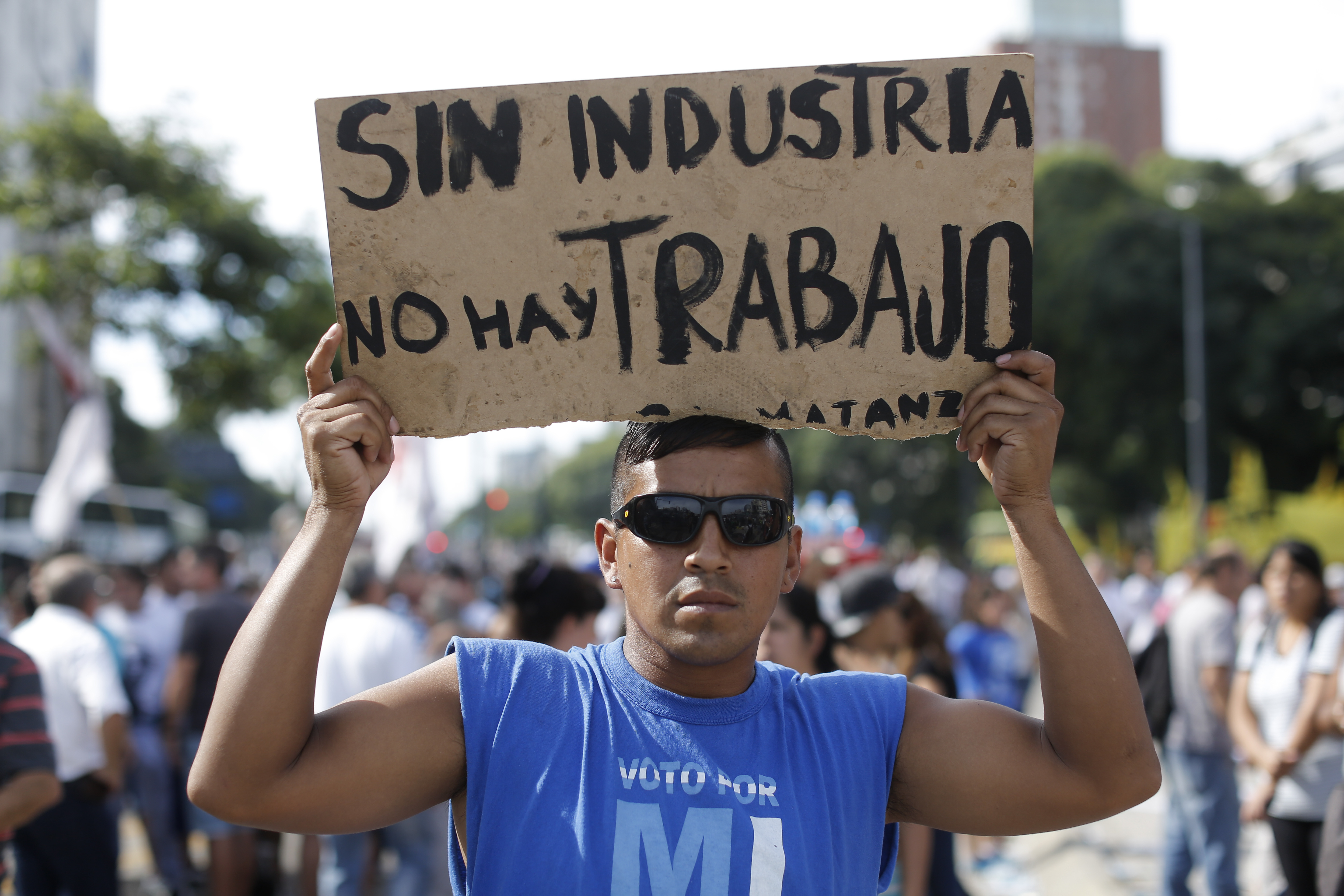 A demonstrator holds a sign that reads in Spanish 