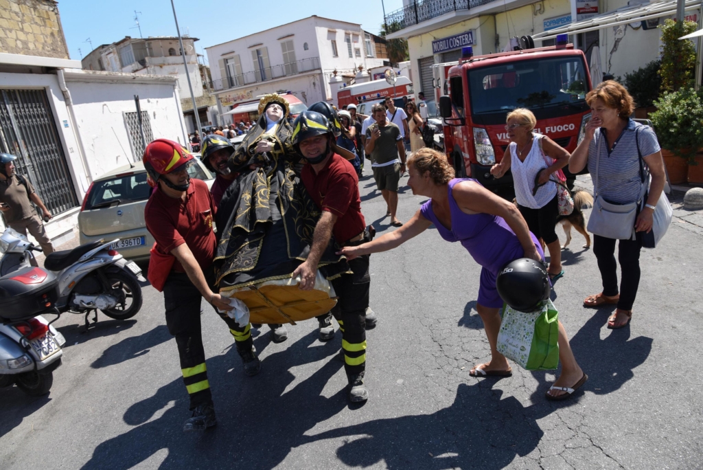 I vigili del fuoco recuperano la statua della Madonna dell'Addolorata dalla chiesa del Purgatorio crollata per il terremoto.