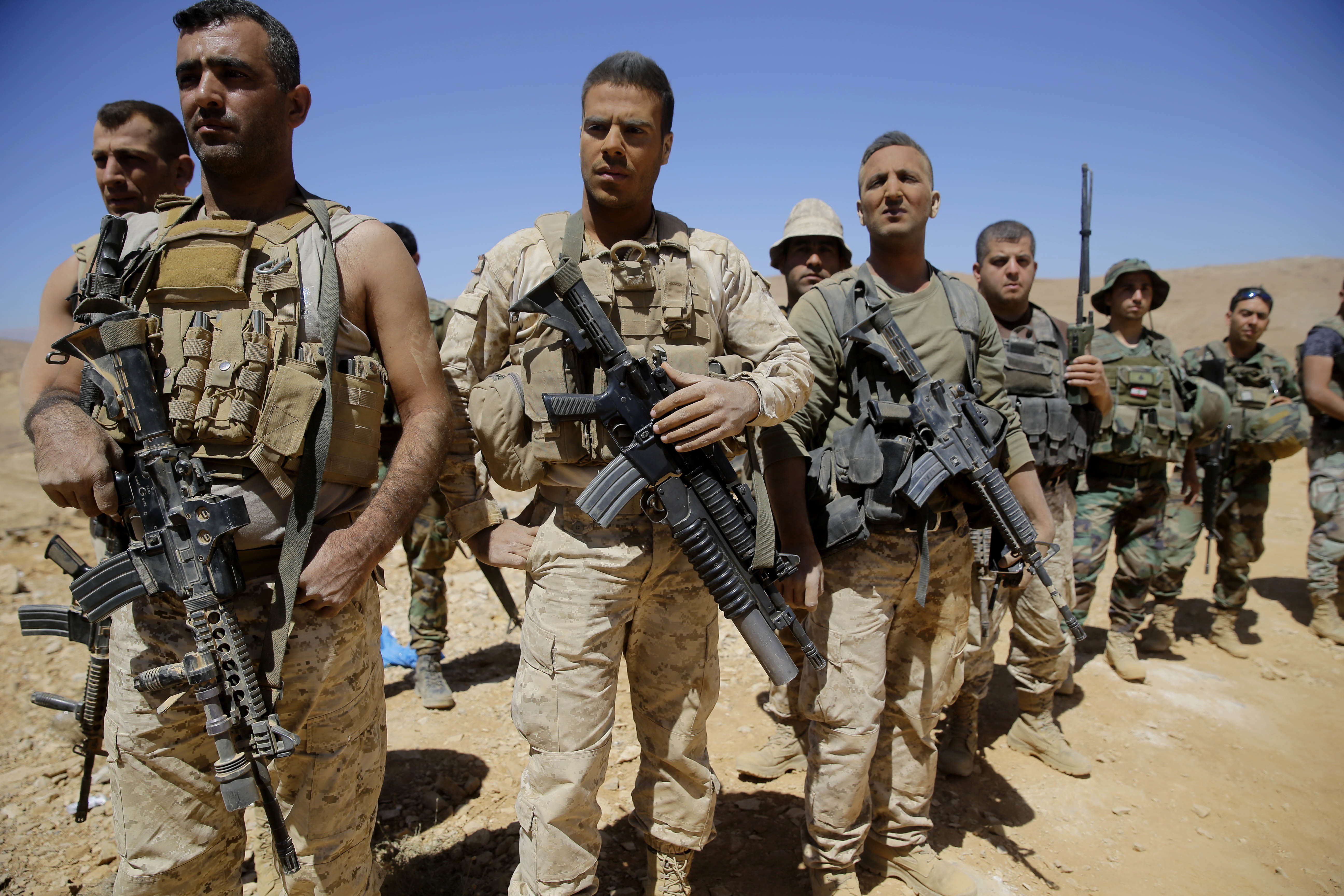 Lebanese soldiers listen to a briefing from an official during a media trip organized by the Lebanese army on the outskirts of Ras Baalbek, northeast Lebanon, Monday, Aug. 28, 2017. Islamic State militants and their families began to evacuate on Monday from a border area between Lebanon and Syria as part of a negotiated deal to end the group's presence there, Lebanese and Syrian media reported. (AP Photo/Hassan Ammar)