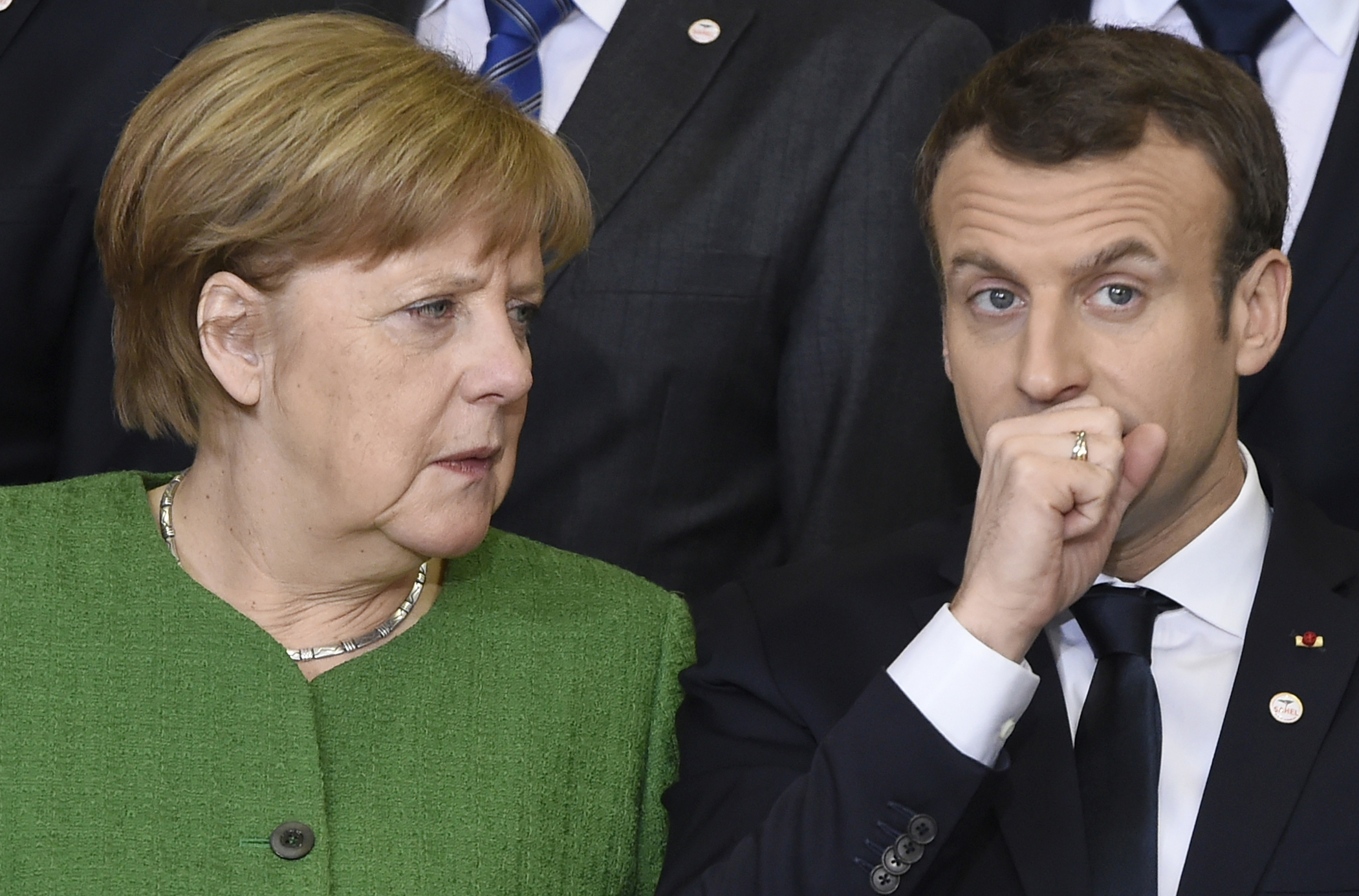 German Chancellor Angela Merkel, left, speaks with French President Emmanuel Macron during a group photo at an EU-Sahel meeting at EU headquarters in Brussels on Friday, Feb. 23, 2018. European Union leaders meet Friday with counterparts from Africa's Sahel in a show of support for the impoverished region fallen prey to extremists and a key transit point for migrants heading to Europe. (John Thys, Pool Photo via AP)
