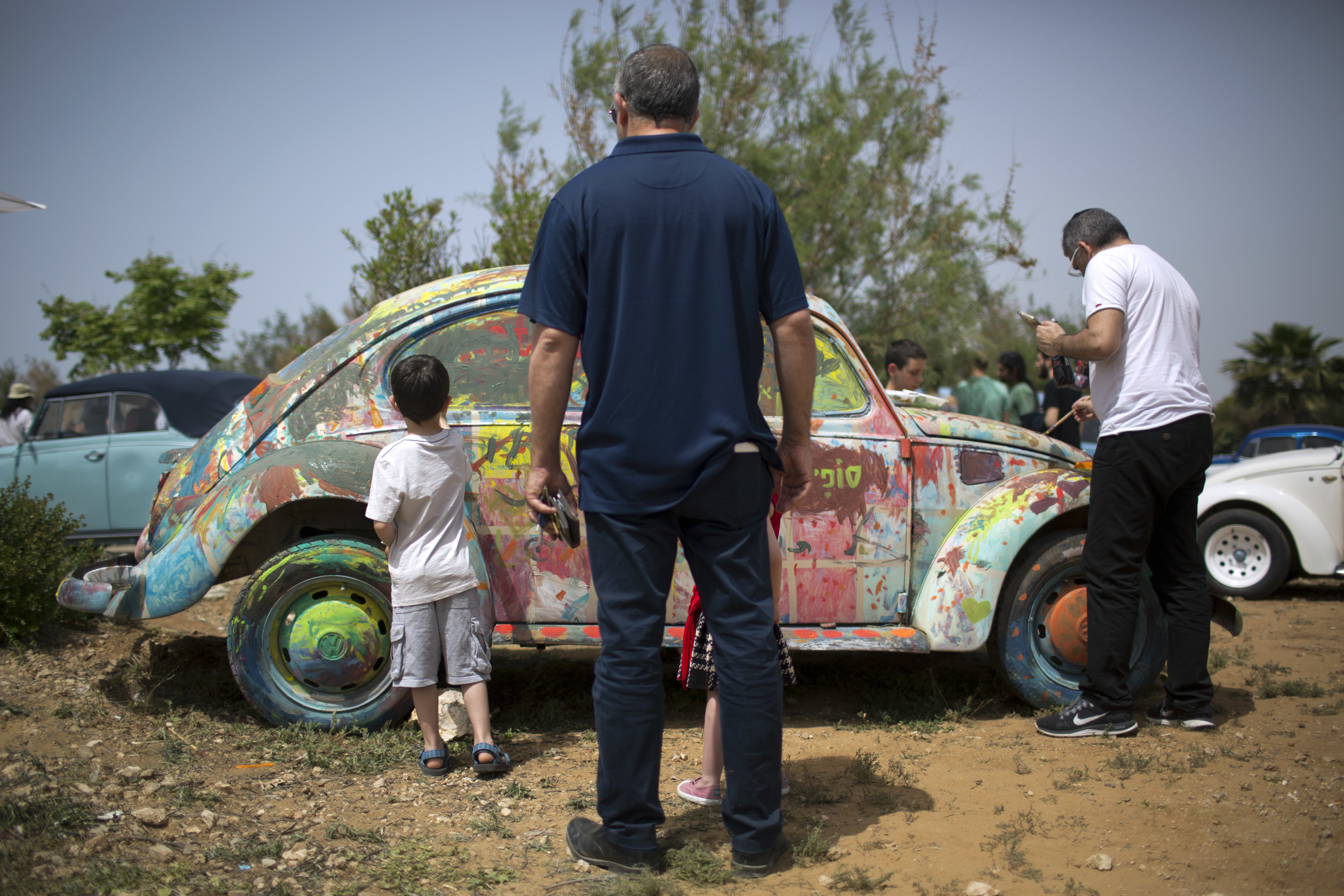 People paints an old Volkswagen Beetle during the annual gathering of the 