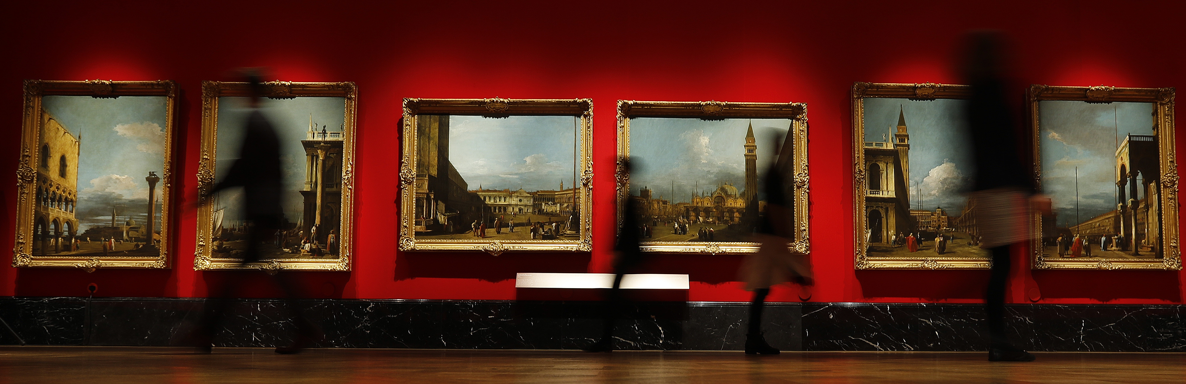 People walk past Canaletto's paintings of Venice views at the Queen's Gallery at Buckingham Palace in London, Thursday, May 18, 2017. A new exhibition reunites two of Canaletto's finest sets of paintings, displayed side by side for the first time in almost 40 years. Canaletto & the Art of Venice is opening on May19, at The Queen's Gallery, Buckingham Palace.(AP Photo/Frank Augstein)