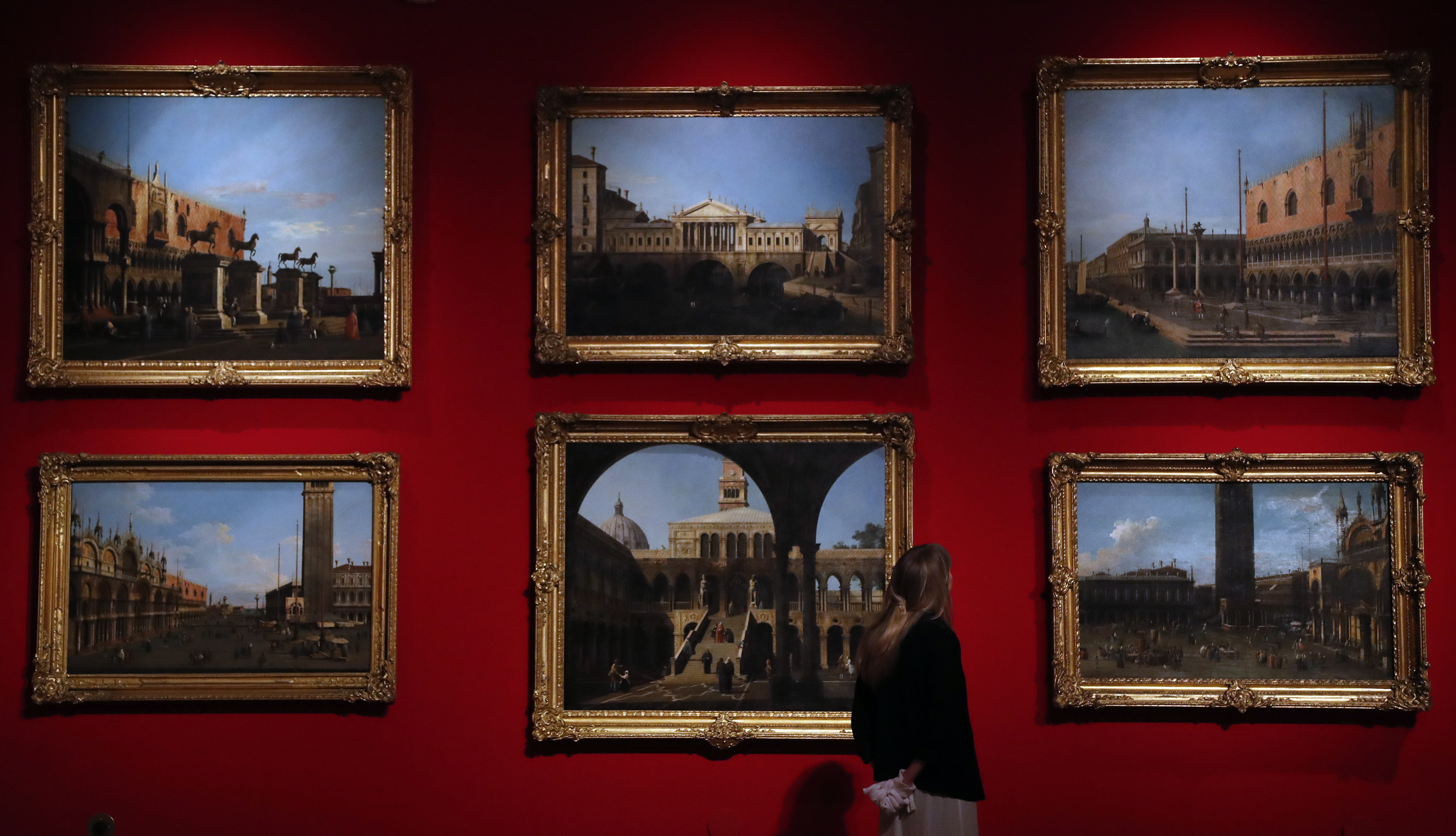 A woman looks at Canaletto's paintings of Venice views at the Queen's Gallery at Buckingham Palace in London, Thursday, May 18, 2017. A new exhibition reunites two of Canaletto's finest sets of paintings, displayed side by side for the first time in almost 40 years. Canaletto & the Art of Venice is opening on May 19, at The Queen's Gallery, Buckingham Palace.(AP Photo/Frank Augstein)