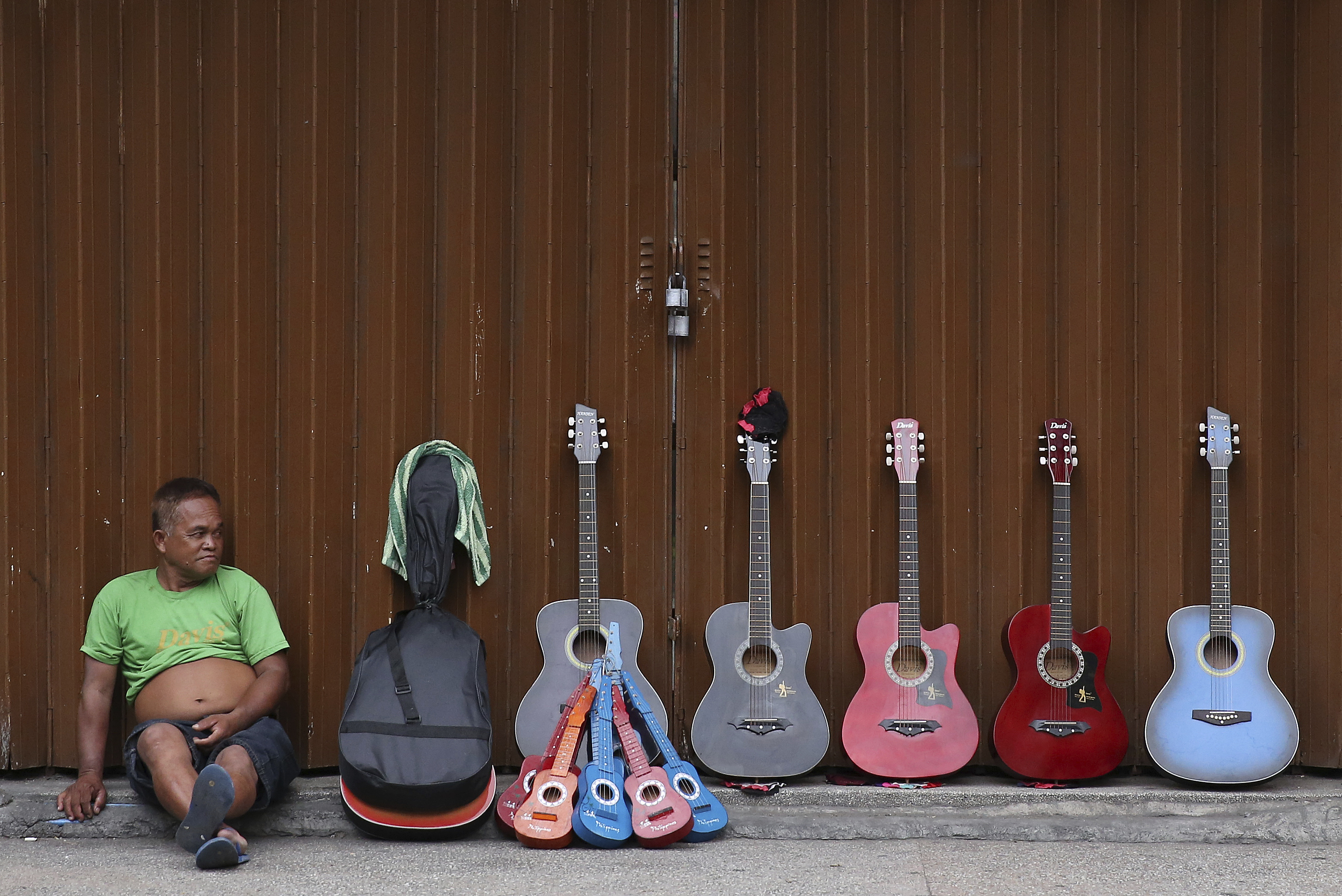 A guitar vendor Michael Hiyas, 57,  waits for customers along a street in Manila, Philippines on Thursday, May 18, 2017. Hiyas says his guitars are often bought by tourists and he earns about P400 (about US$8) a day. (AP Photo/Aaron Favila)