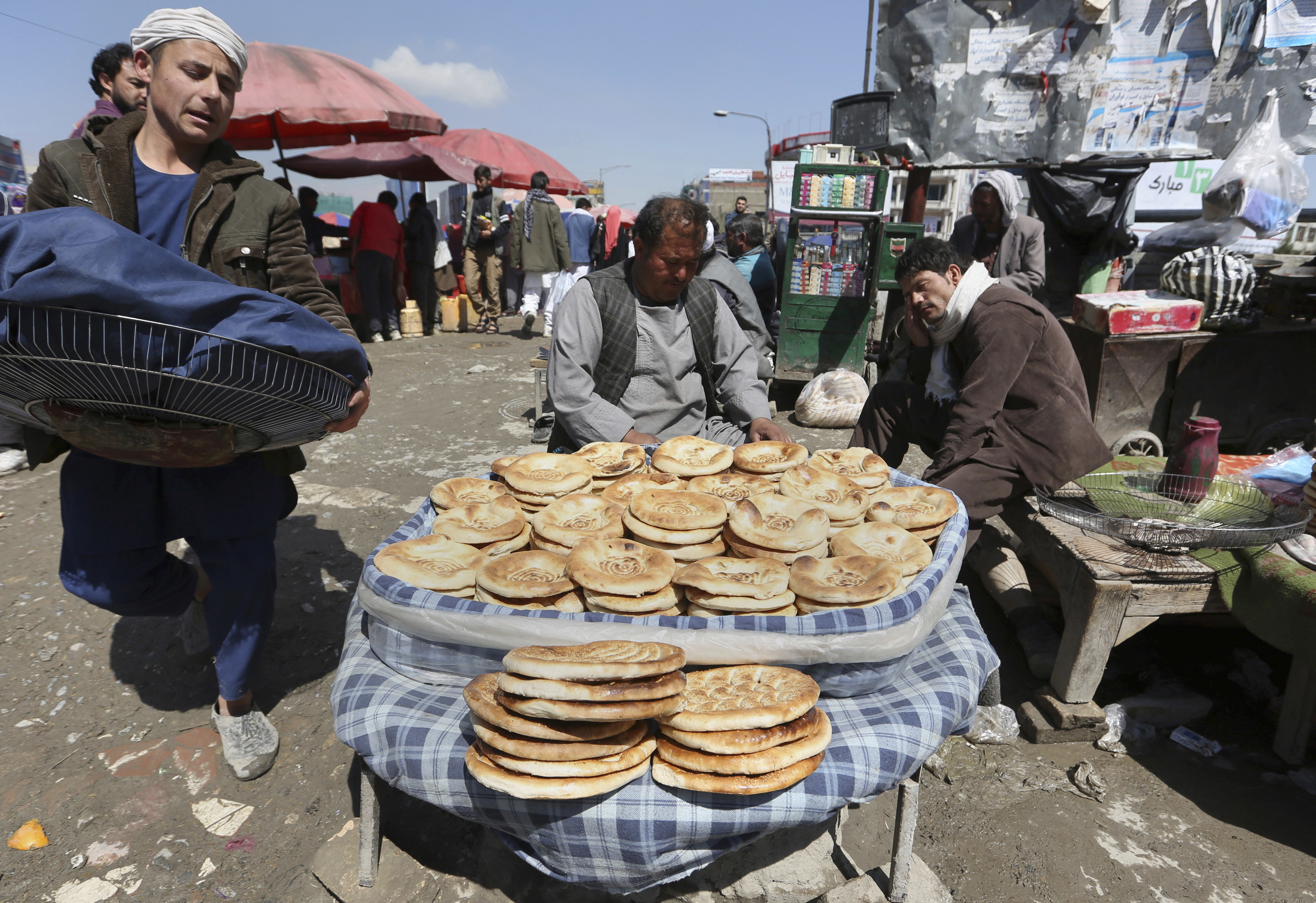 An Afghan street vendor, center, sells bread in Kabul, Afghanistan, Thursday, April 6, 2017. (AP Photo/Rahmat Gul)