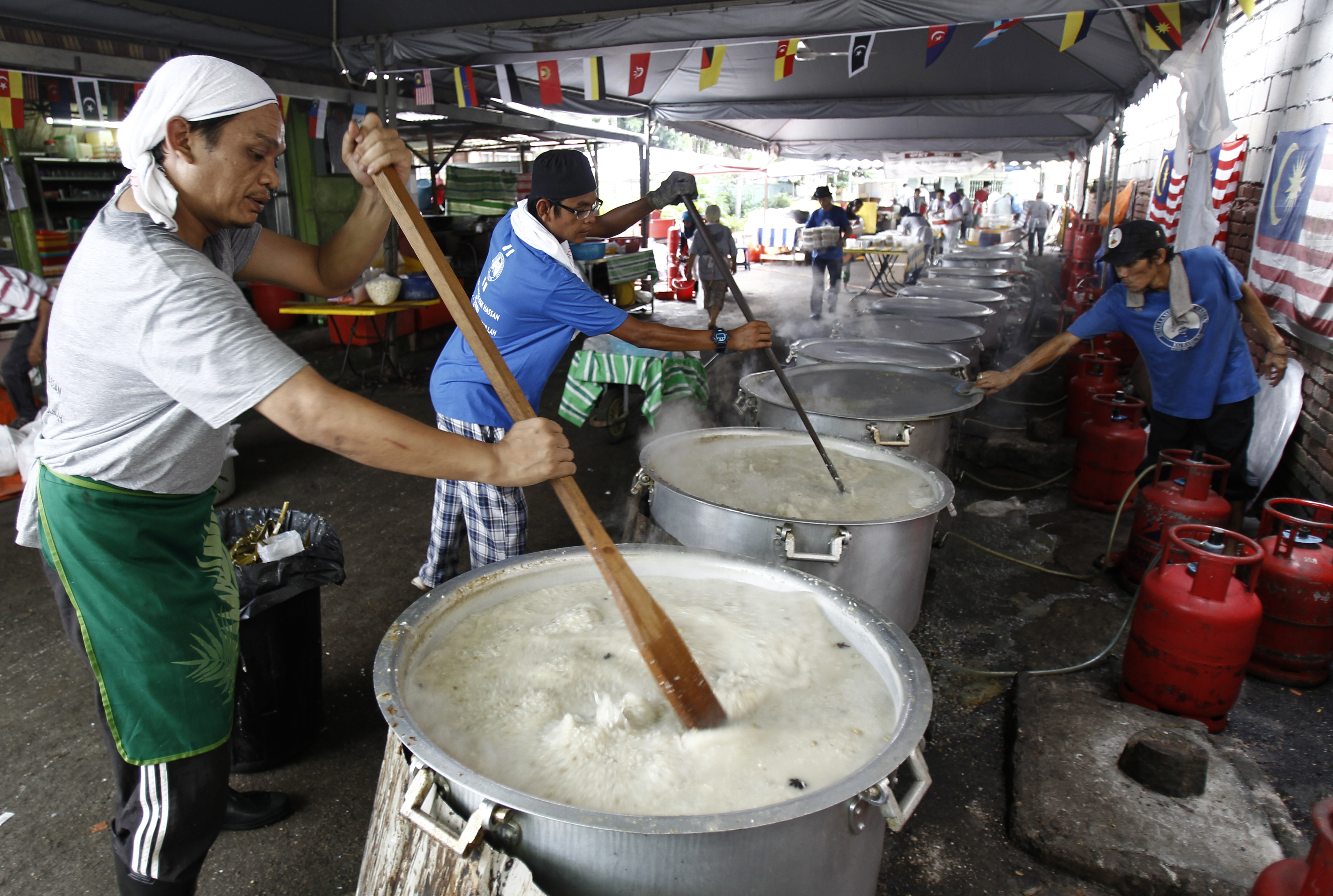 Malaysian Muslims cook large pots of Bubur Lambuk porridge in the Kampung Baru village in Kuala Lumpur, Malaysia on Thursday, June 1, 2017. Bubur Lambuk is a type of Malay rice porridge that is cooked and distributed in many places during the fasting month of Ramadan. (AP Photo/Daniel Chan)