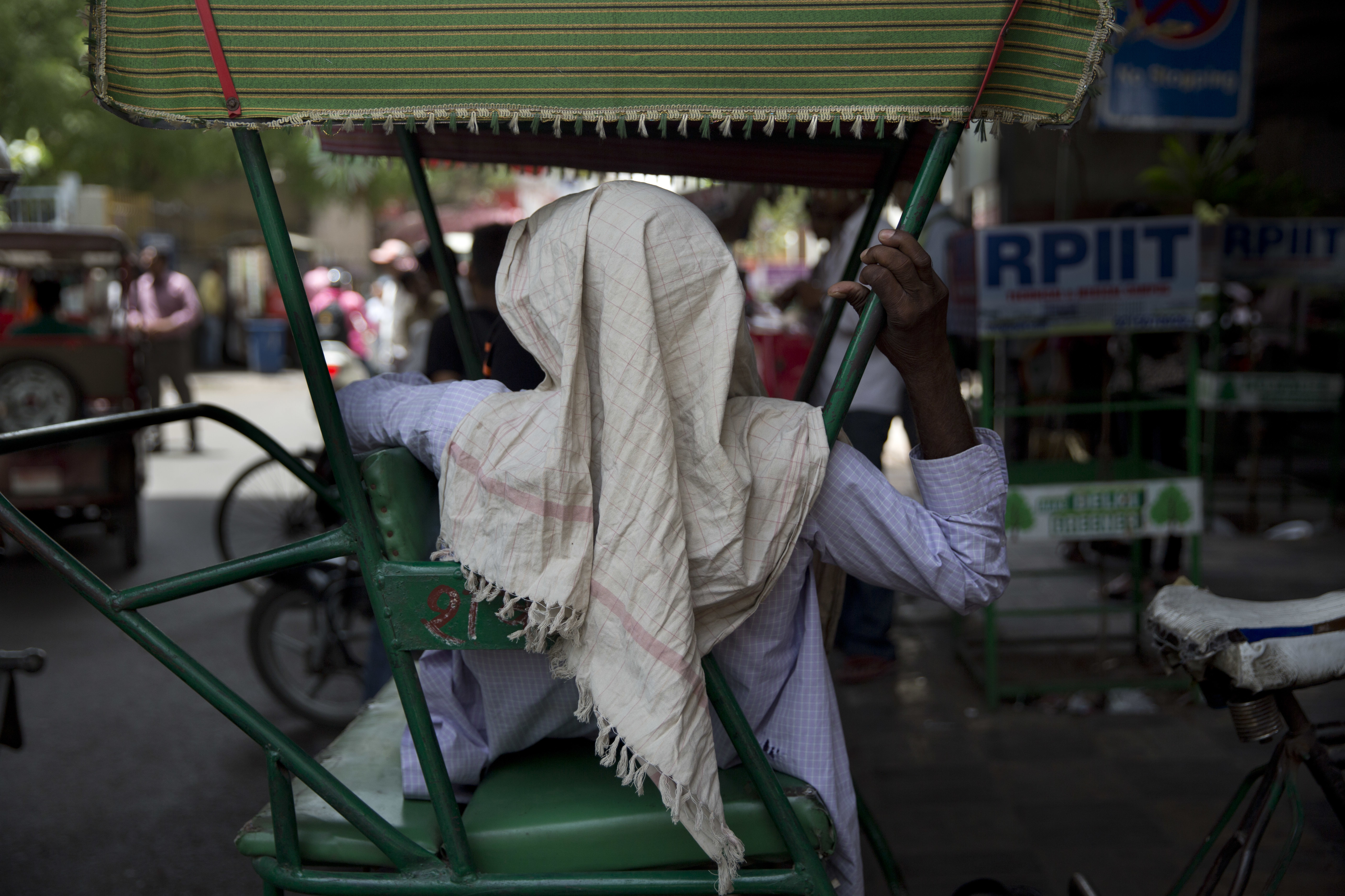 An Indian rickshaw puller with his head wrapped in a scarf to wipe sweat, waits for customers on hot day in New Delhi, India, Monday, June 5, 2017. Most parts of northern India is reeling under intense heat wave conditions with the temperature crossing over 43 degrees Celsius (109.4 Fahrenheit).(AP Photo/Tsering Topgyal)