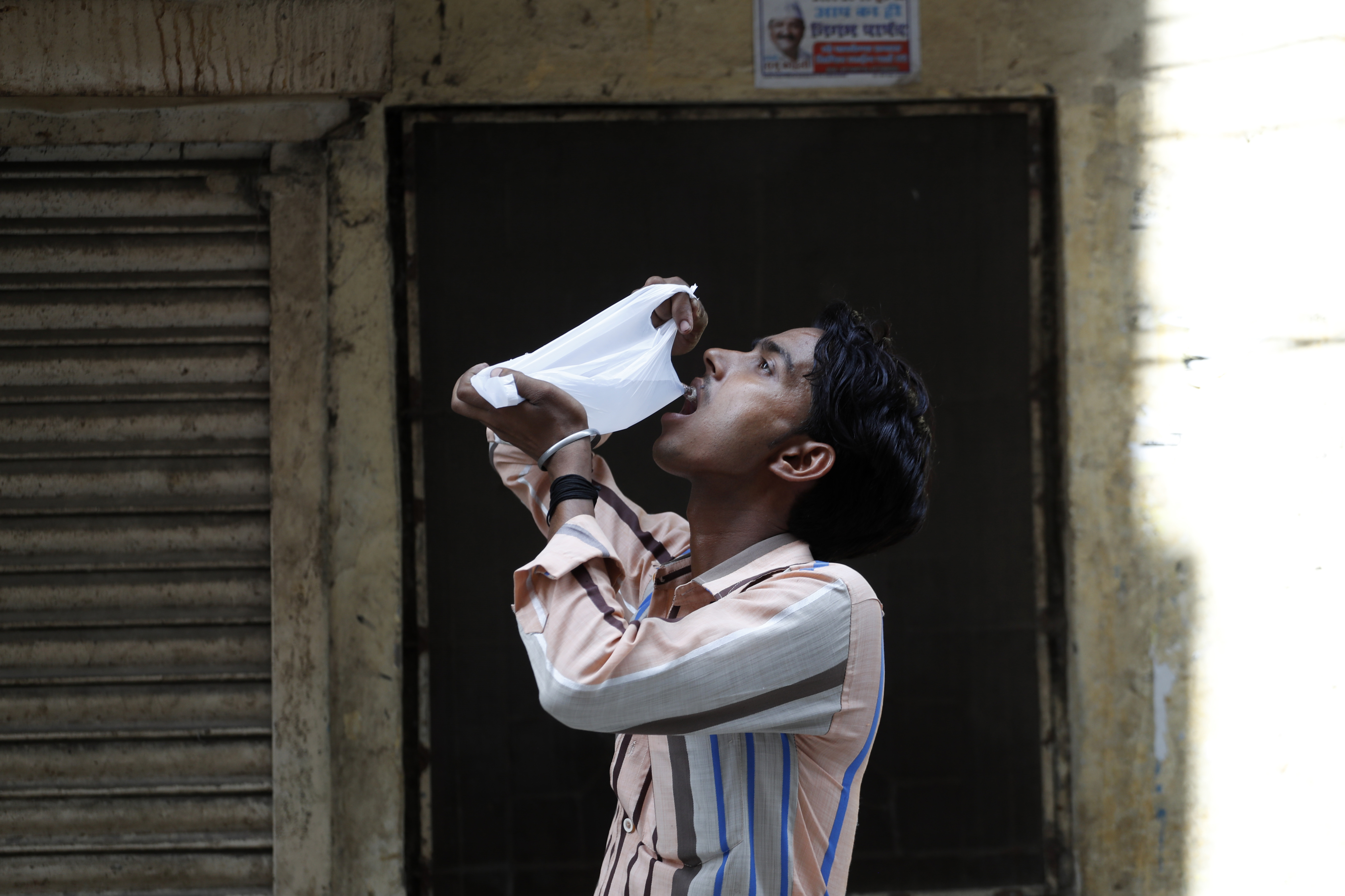 An Indian man drinks water from a plastic bag on a hot summer day in New Delhi, India, Monday, June 5, 2017. Most parts of northern India is reeling under intense heat wave conditions with the temperature crossing over 43 degrees Celsius (109.4 Fahrenheit).(AP Photo/Tsering Topgyal)
