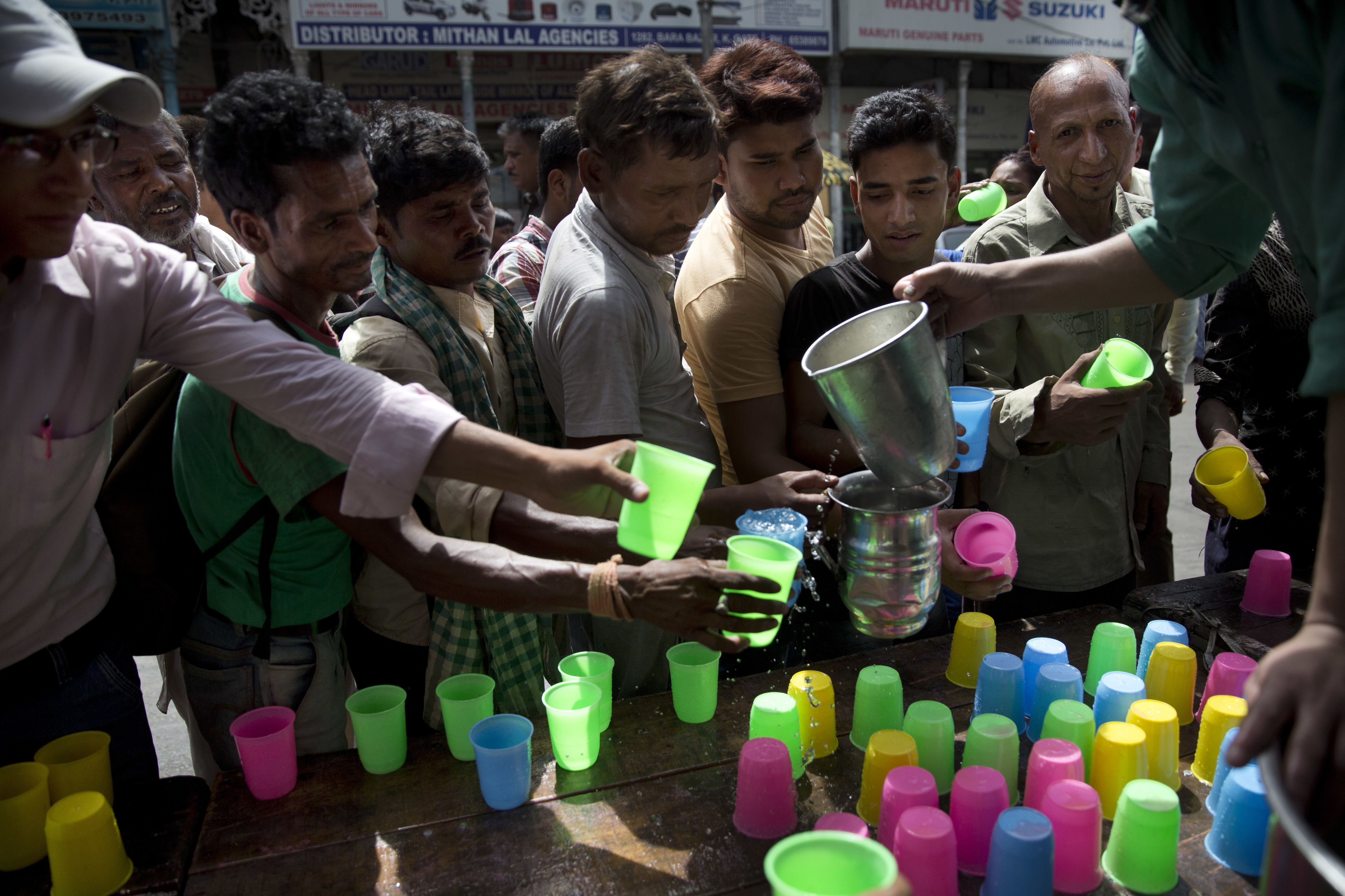 Indians stand in line to get cold drink being freely distributed by a roadside on hot summer day in New Delhi, India, Monday, June 5, 2017. Most parts of northern India is reeling under intense heat wave conditions with the temperature crossing over 43 degrees Celsius (109.4 Fahrenheit).(AP Photo/Tsering Topgyal)