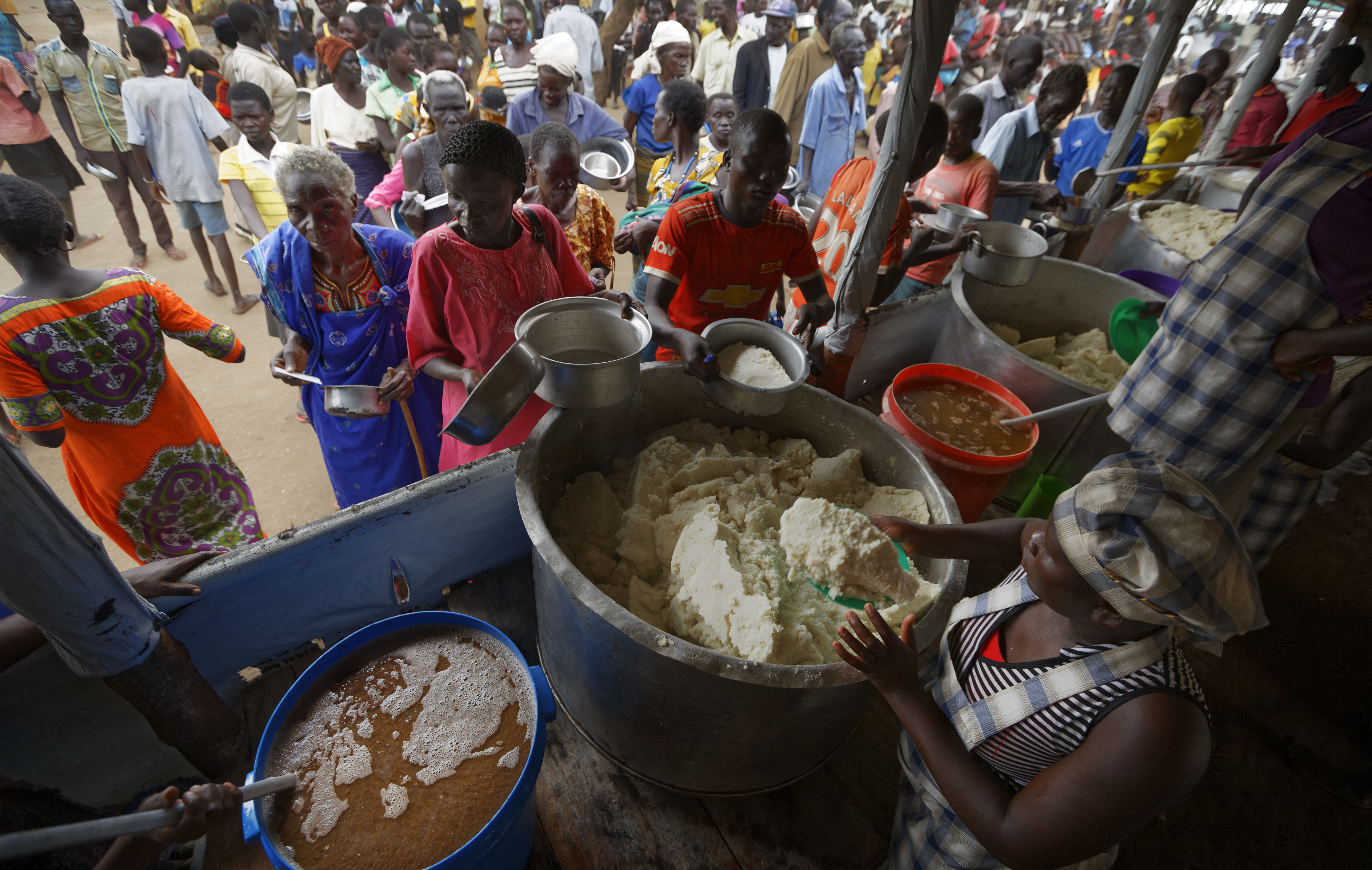 South Sudanese refugees queue to receive a lunch of maize mash and beans, at the Imvepi reception centre, where newly arrived refugees are processed before being allocated plots of land in nearby Bidi Bidi refugee settlement, in northern Uganda, Tuesday, June 6, 2017. Bidi Bidi is a sprawling complex of mud-brick houses that is now the world's largest refugee settlement holding some of those who fled the civil war in South Sudan, which has killed tens of thousands and driven out more than 1.5 million people in the past three years, creating the world's largest refugee crisis. (AP Photo/Ben Curtis)