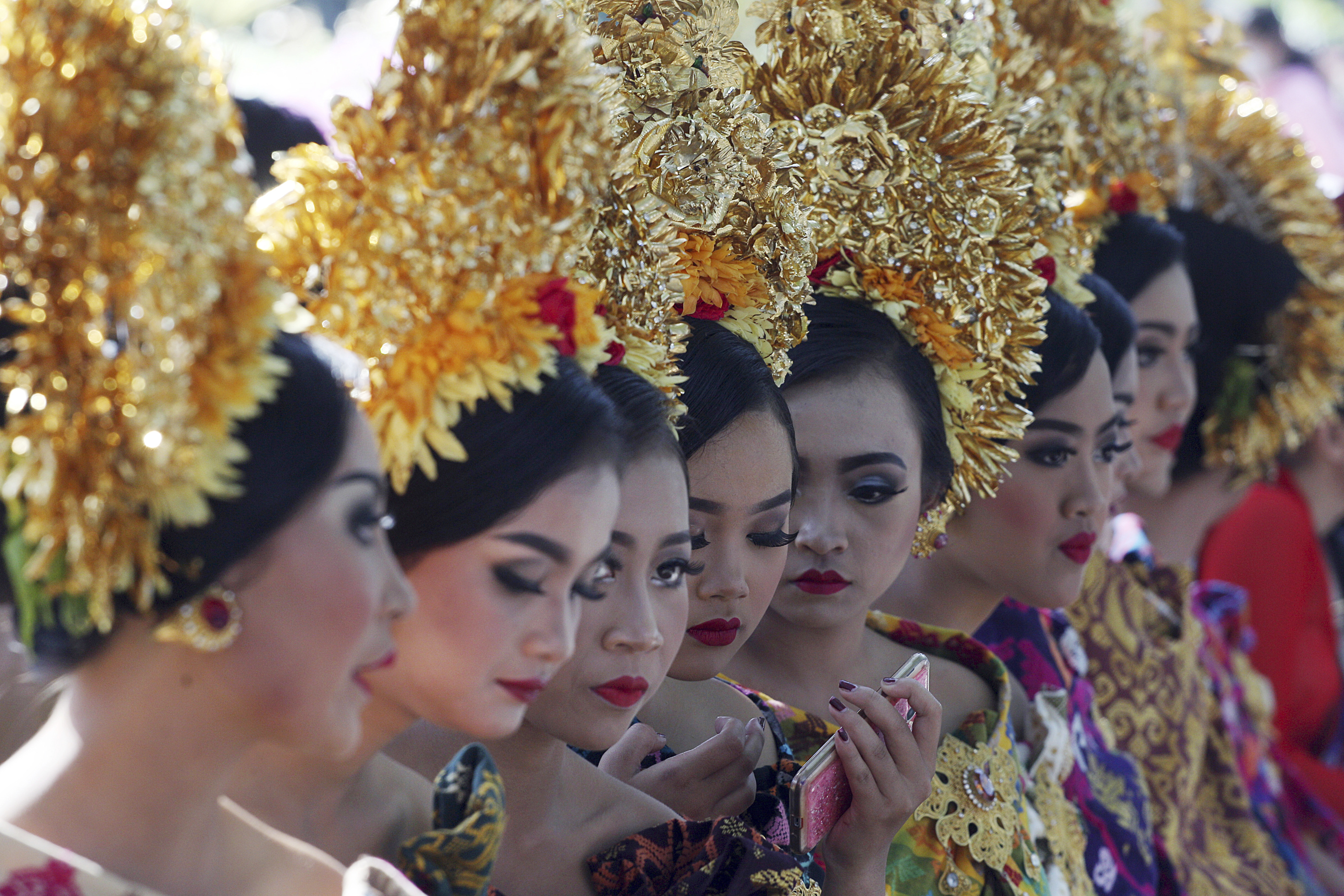 Women in traditional dress wait for a parade during the Bali Arts Festival in Bali, Indonesia, Saturday, June 10, 2017. A month-long annual festival started on Saturday. (AP Photo/Firdia Lisnawati)