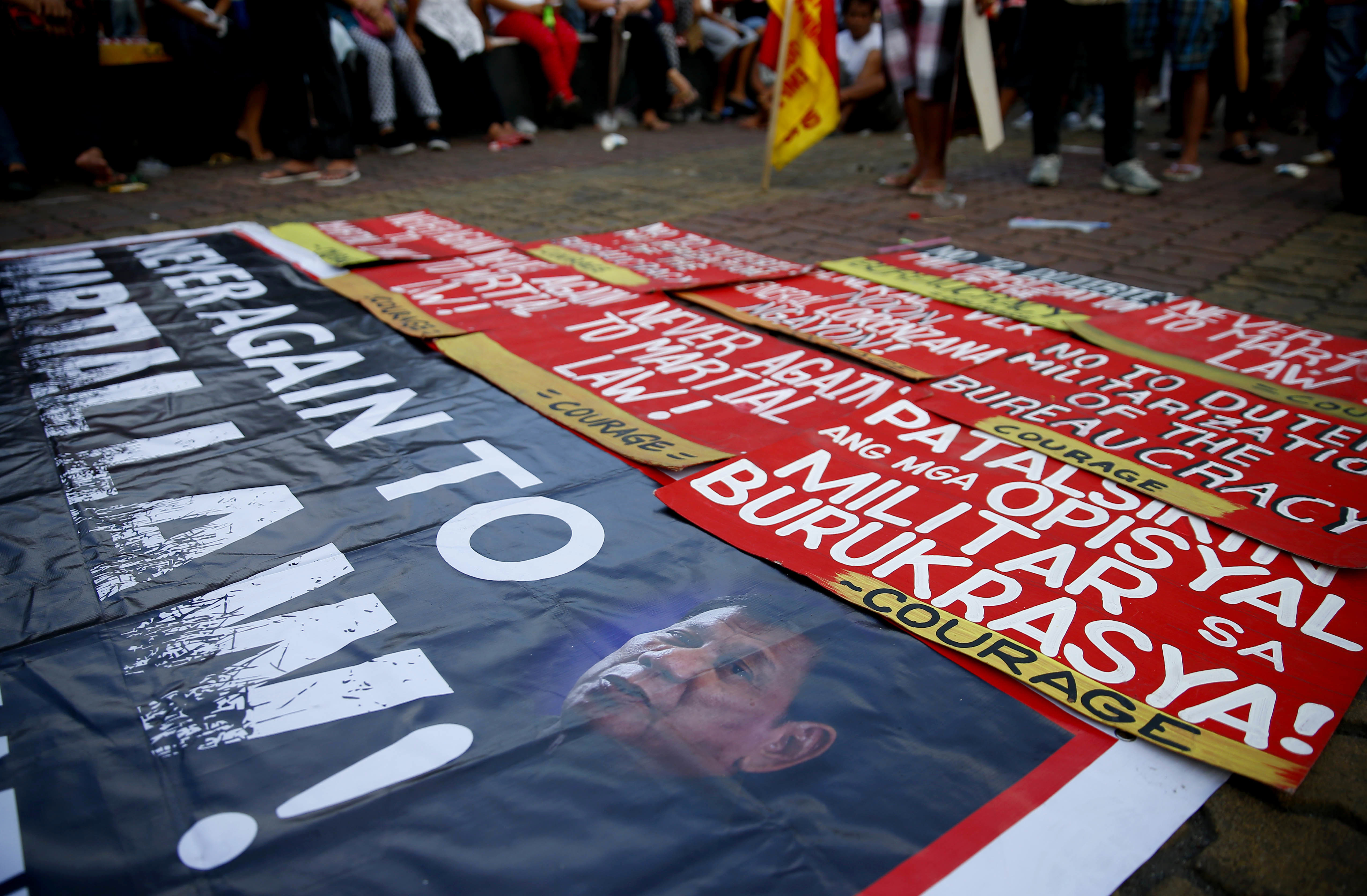 Protesters place a tarpaulin poster bearing a photo of Philippine President Rodrigo Duterte and placards with their messages on the pavement during a rally near the Presidential Palace to denounce the Martial Law declaration by Duterte after Muslim militants laid a siege of Marawi city in southern Philippines for three weeks, Monday, June 12, 2017 in Manila, Philippines. The protesters also denounced the killings by Duterte's bloody anti-drug crackdown. (AP Photo/Bullit Marquez)