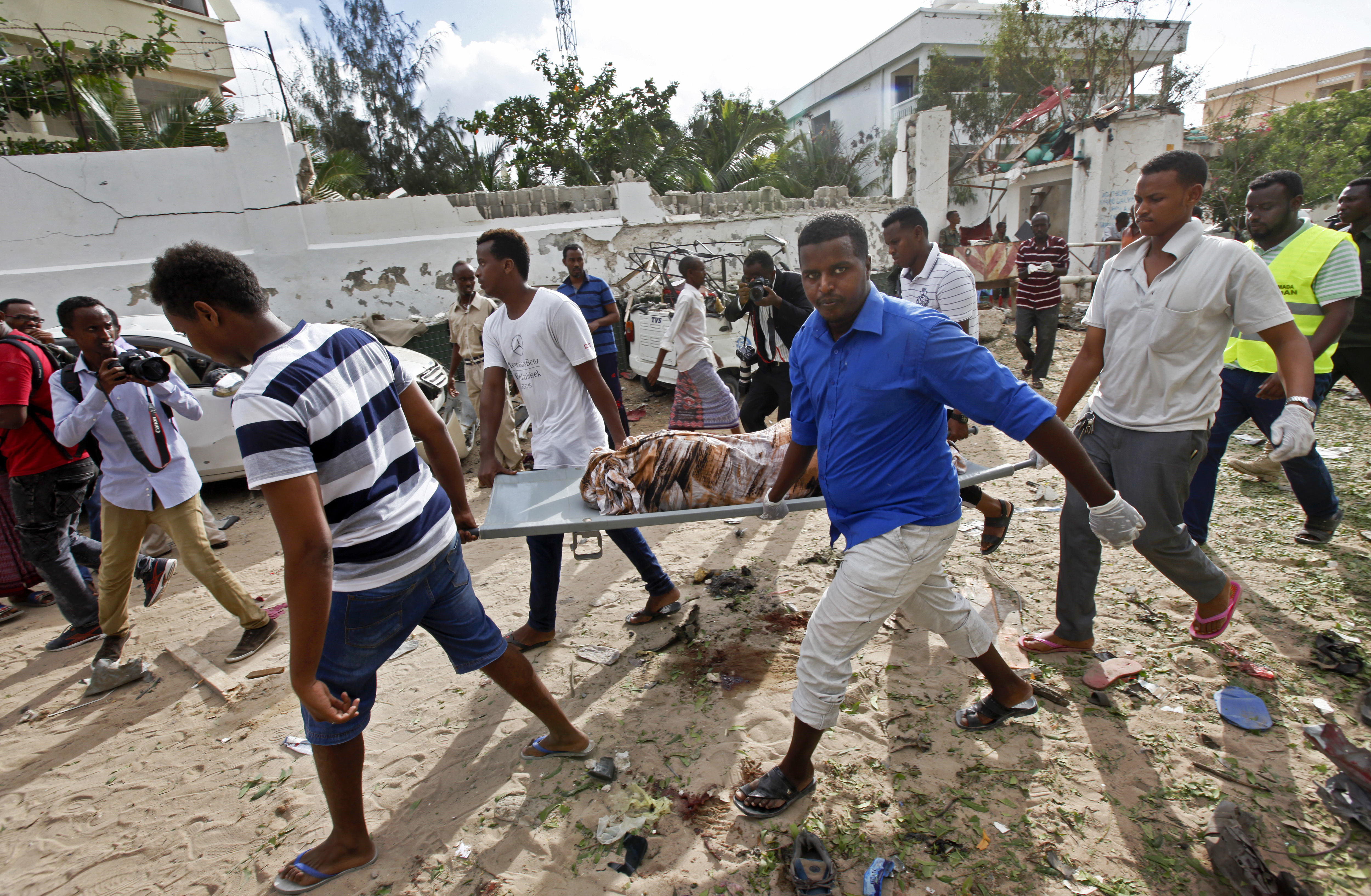 Somali men carry away the body of a civilian who was killed in a militant attack on a restaurant in Mogadishu, Somalia Thursday, June 15, 2017. Somalia's security forces early Thursday morning ended a night-long siege by al-Shabab Islamic extremists at the popular 