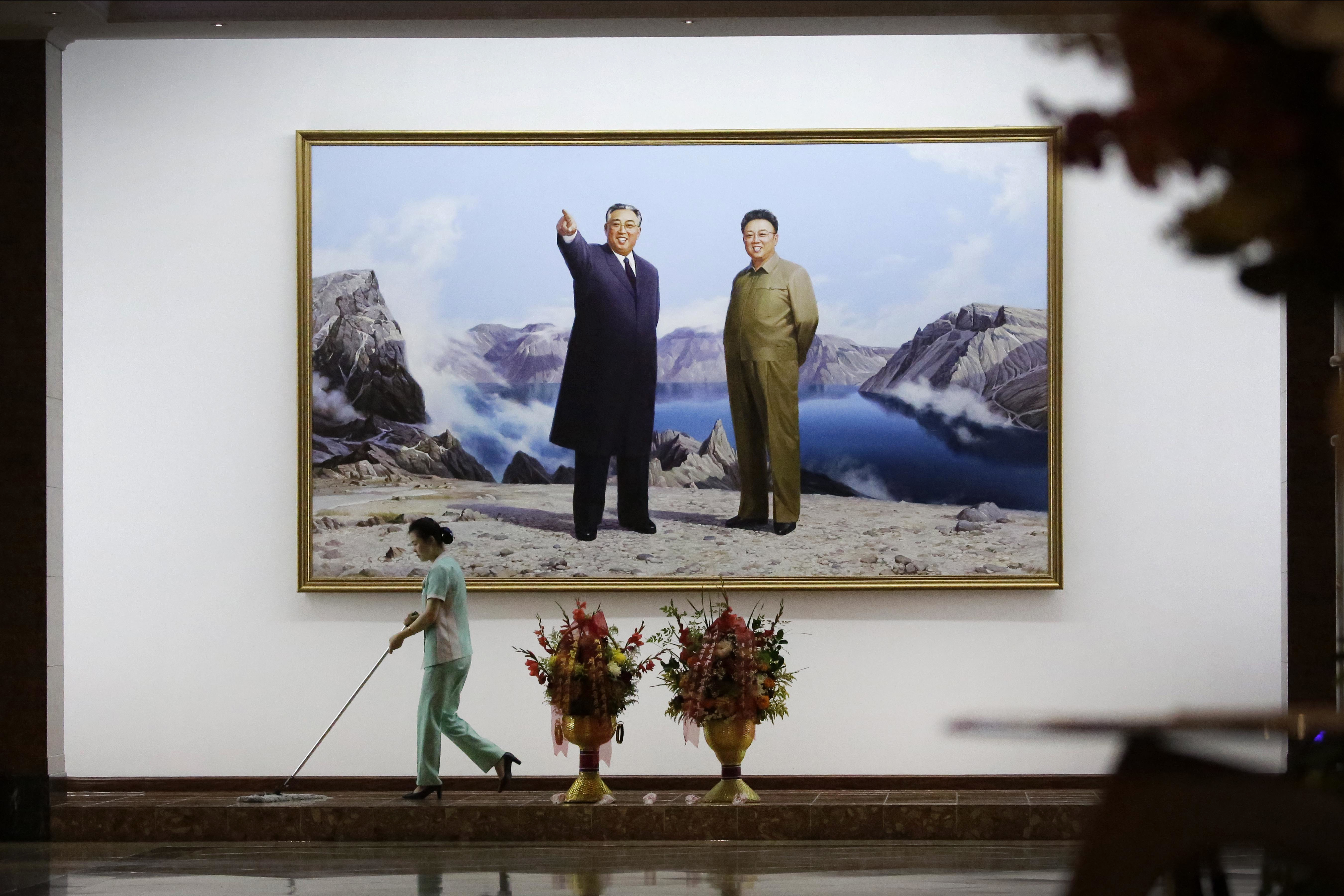 A hotel staff member mops the floor where a picture featuring portraits of the late North Korean leaders Kim Il Sung, left, and Kim Jong Il decorates the lobby wall Monday, June 19, 2017, in Pyongyang, North Korea. (AP Photo/Wong Maye-E)