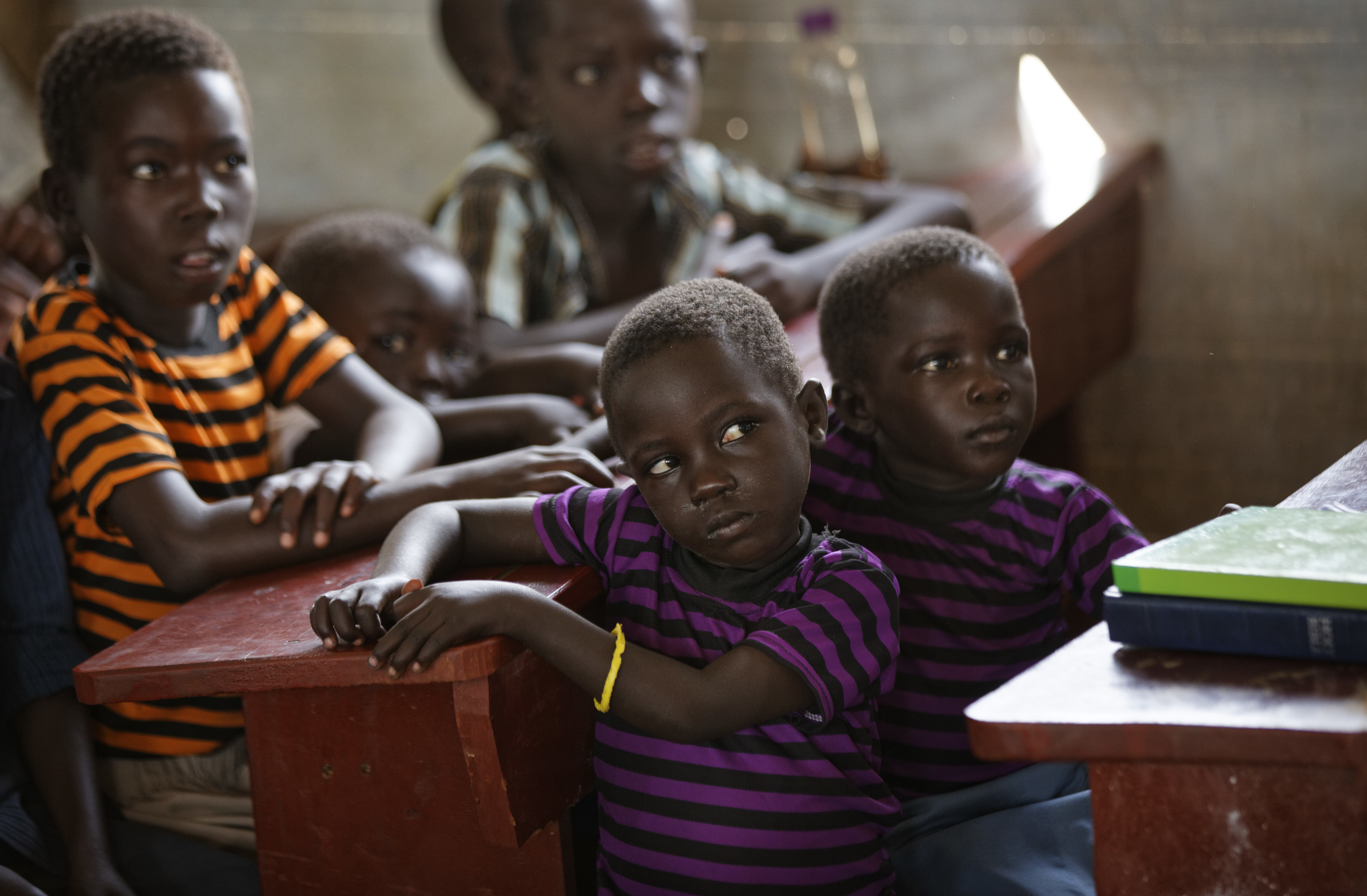 In this photo taken Sunday, June 4, 2017, young members of the congregation listen at a Sunday service at the United Church, which is held in a school classroom tent, in Bidi Bidi refugee settlement in northern Uganda. The South Sudanese refugees meet in open-air churches rigged from timber with seats made only from planks of wood or logs drilled into the ground, yet these churches for the born-again Christians are oases of joy among the daily humiliations that come with rebuilding their lives. (AP Photo/Ben Curtis)
