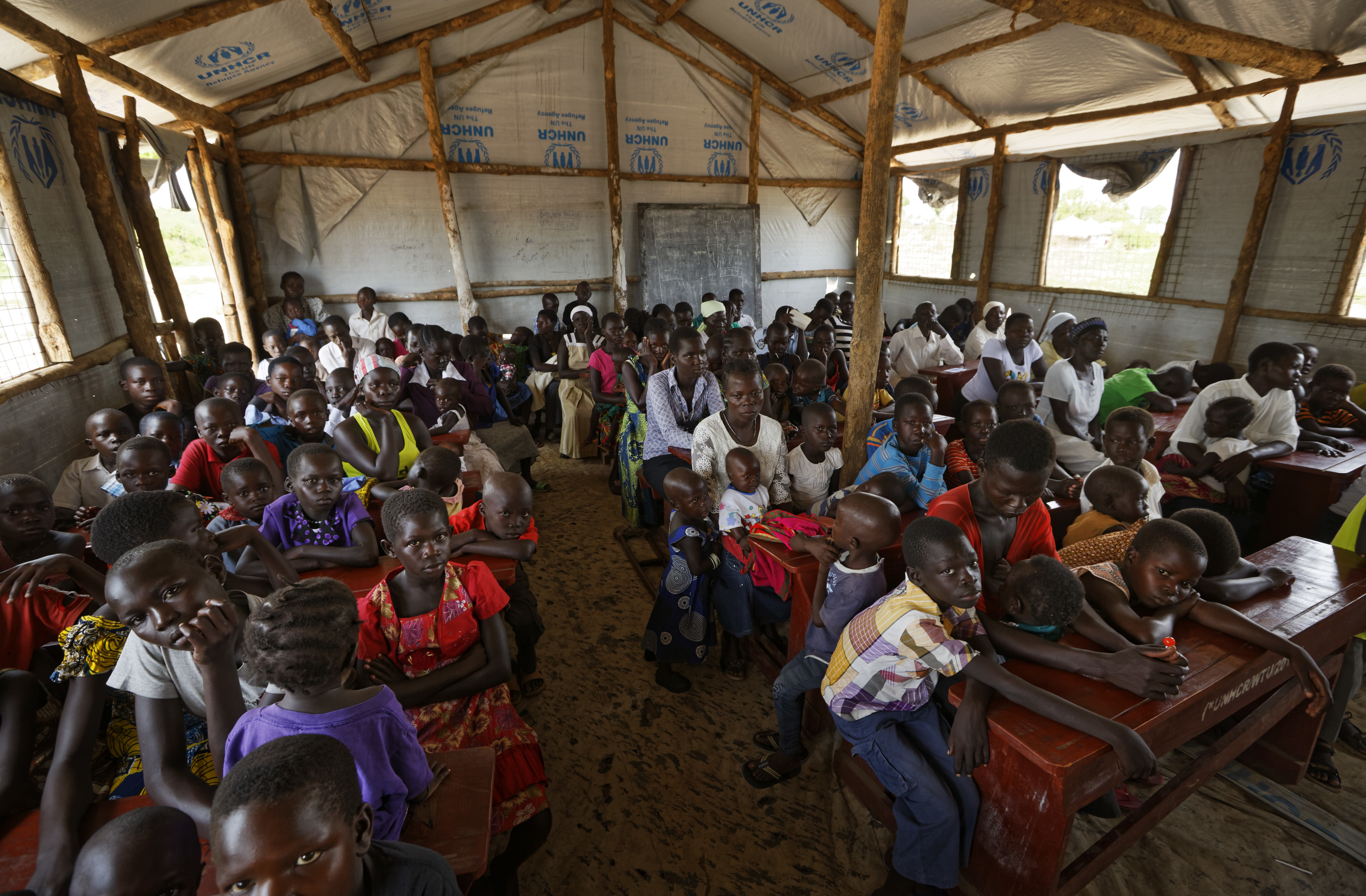 In this photo taken Sunday, June 4, 2017, the congregation attends a Sunday service at the United Church, which is held in a school classroom tent, in Bidi Bidi refugee settlement in northern Uganda. The South Sudanese refugees meet in open-air churches rigged from timber with seats made only from planks of wood or logs drilled into the ground, yet these churches for the born-again Christians are oases of joy among the daily humiliations that come with rebuilding their lives. (AP Photo/Ben Curtis)