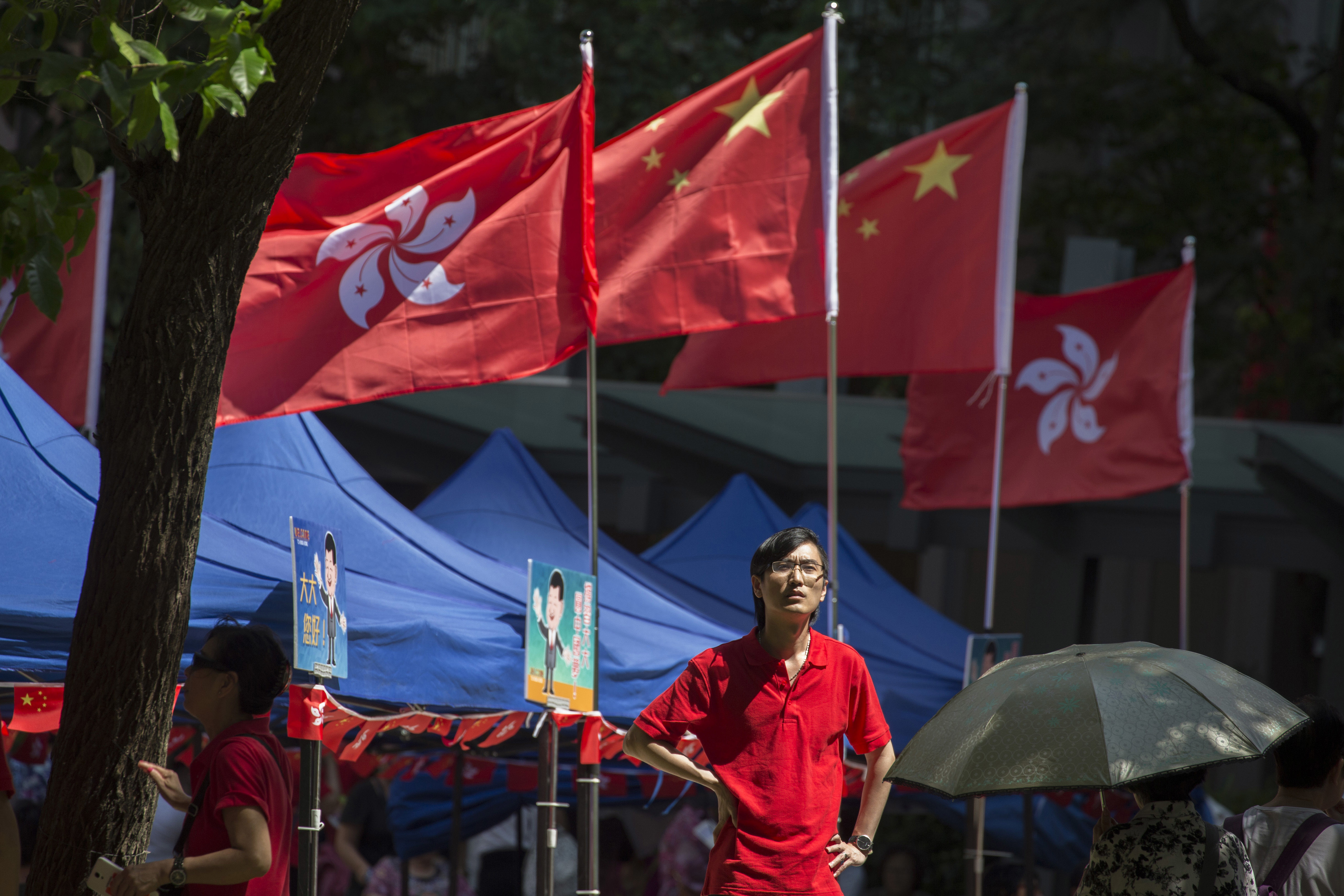 A man stands near Chinese and Hong Kong flags at an event to show support for the Chinese president's visit at a gathering in Hong Kong, Thursday, June 29, 2017. Hong Kong is planning a big party as it marks 20 years under Chinese rule. Fireworks, a gala variety show and Chinese military displays are among the official events planned to coincide with a visit by Xi starting Thursday for the occasion. (AP Photo/Ng Han Guan)