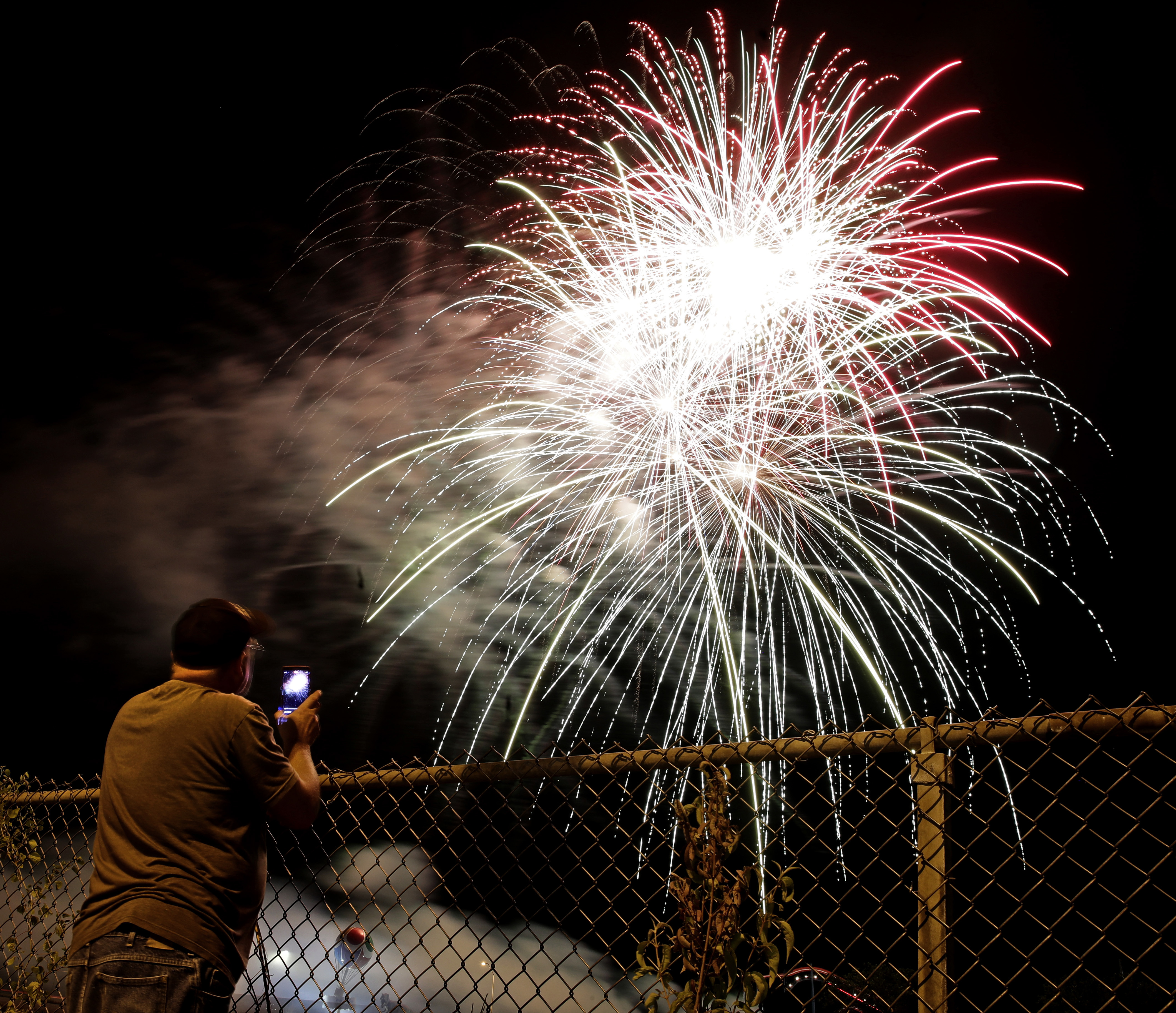 A man watches a fireworks display for Independence Day at Worlds of Fun amusement park Monday, July 3, 2017, in Kansas City, Mo. (AP Photo/Charlie Riedel)