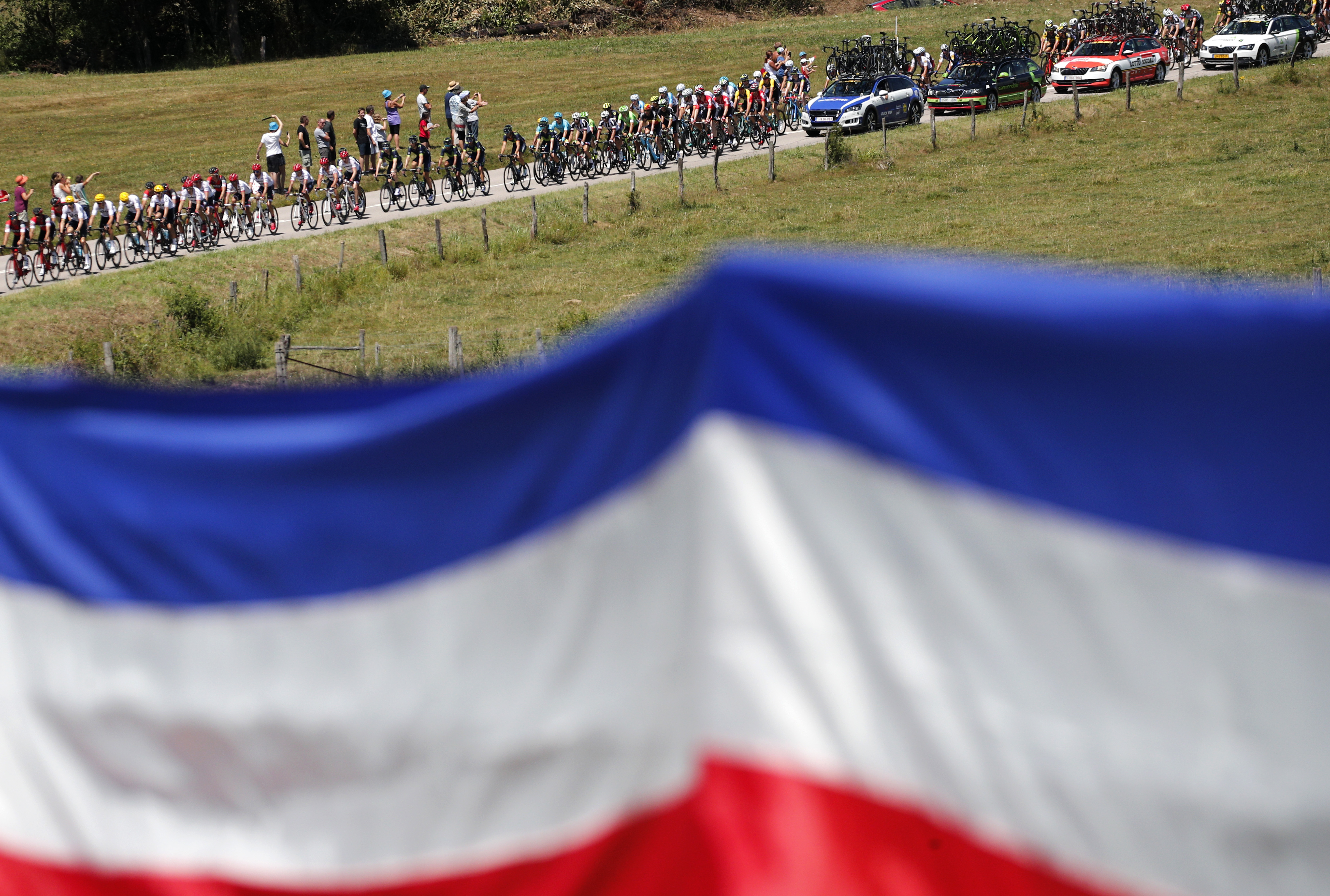 A french flag hangs from a fence as the pack approaches during the fifth stage of the Tour de France cycling race over 160.5 kilometers (99.7 miles) with start in Vittel and finish in La Planche des Belles Filles, France, Wednesday, July 5, 2017. (AP Photo/Christophe Ena)