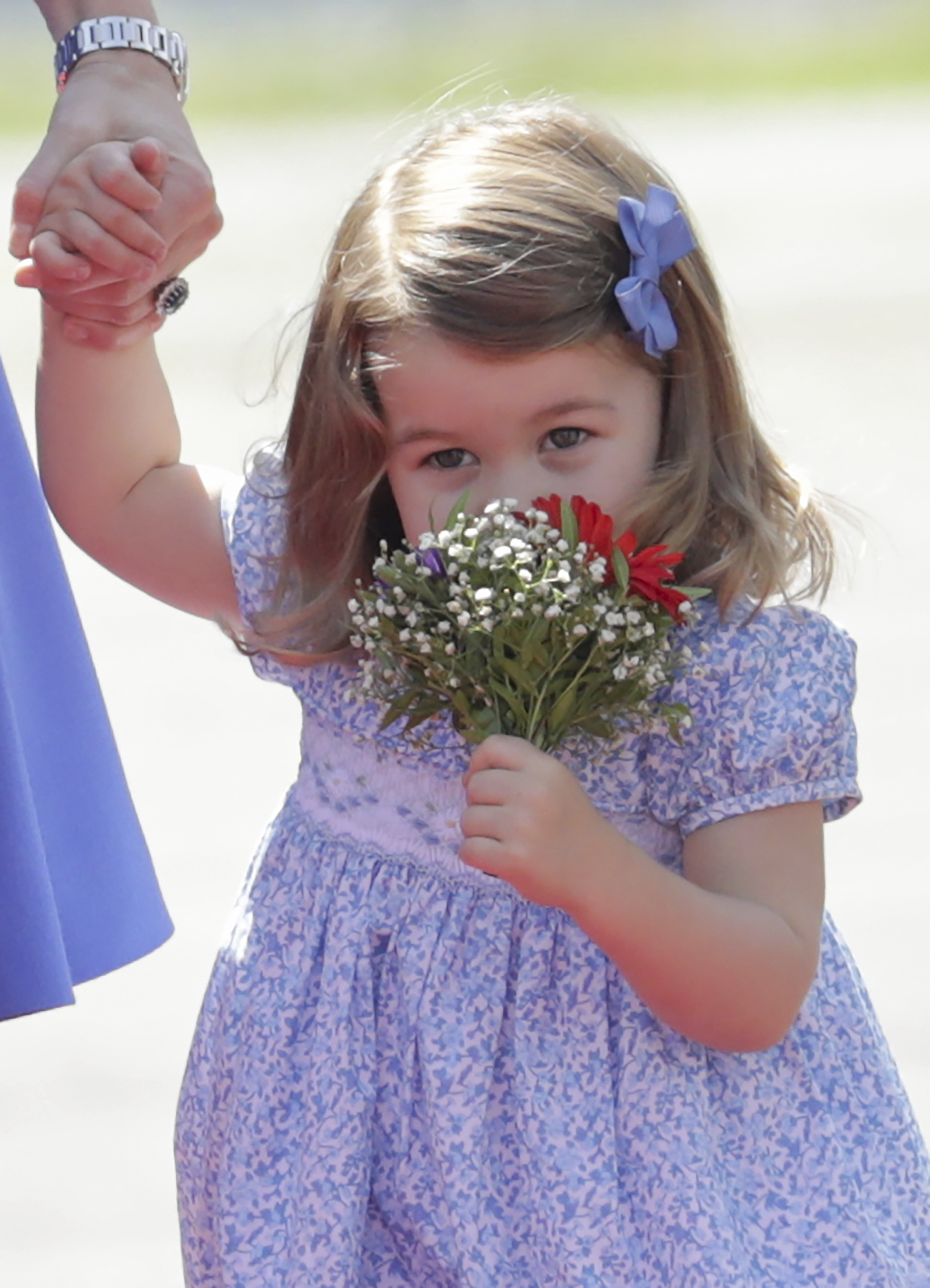 Charlotte, the daughter of Britain's Prince William and his wife Catherine, Duchess of Cambridge, smells a bunch of flowers after arriving at Tegel Airport in Berlin, Germany, 19 July 2017. Photo by: Kay Nietfeld/picture-alliance/dpa/AP Images