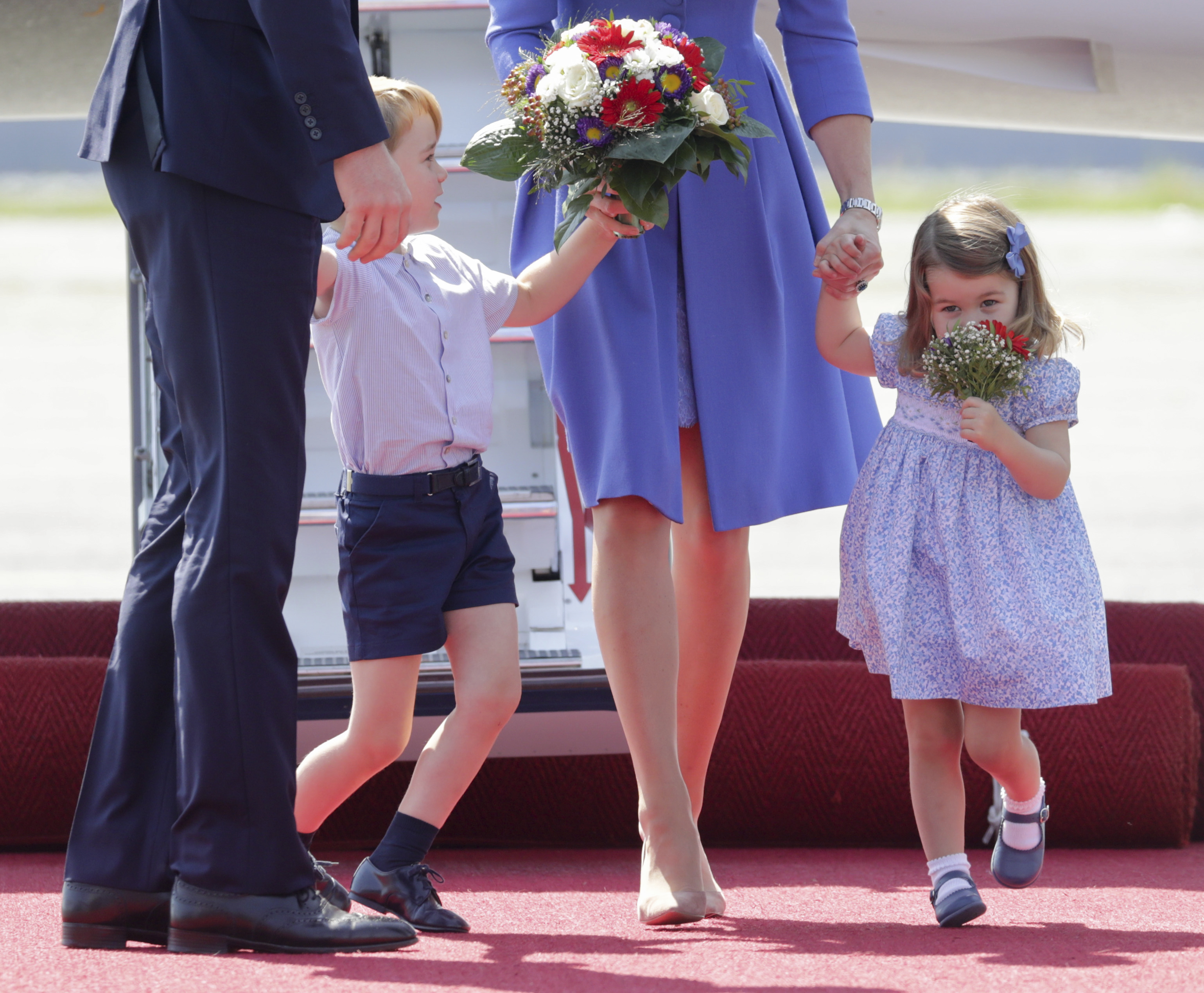 Charlotte, the daughter of Britain's Prince William and his wife Catherine, Duchess of Cambridge, smells a bunch of flowers beside her brother Prince George'after arriving at Tegel Airport in Berlin, Germany, 19 July 2017. Photo by: Kay Nietfeld/picture-alliance/dpa/AP Images
