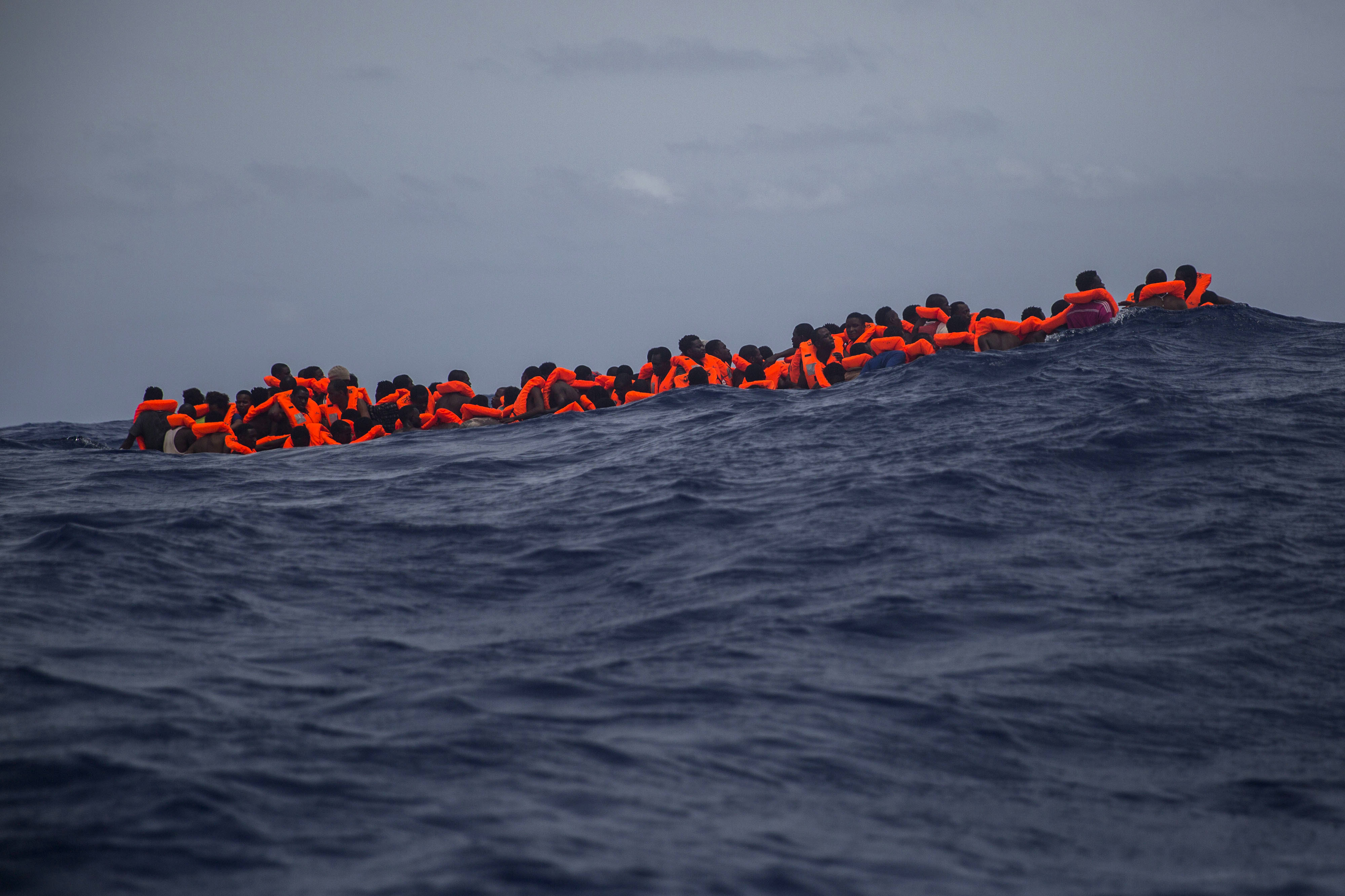 Sub saharan migrants wait to be rescued by aid workers of Spanish NGO Proactiva Open Arms in the Mediterranean Sea, about 15 miles north of Sabratha, Libya on Tuesday, July 25, 2017. More than 120 migrants were rescued Tuesday from the Mediterranean Sea while 13 more —including pregnant women and children— died in a crammed rubber raft, according to a Spanish rescue group. (AP Photo/Santi Palacios)