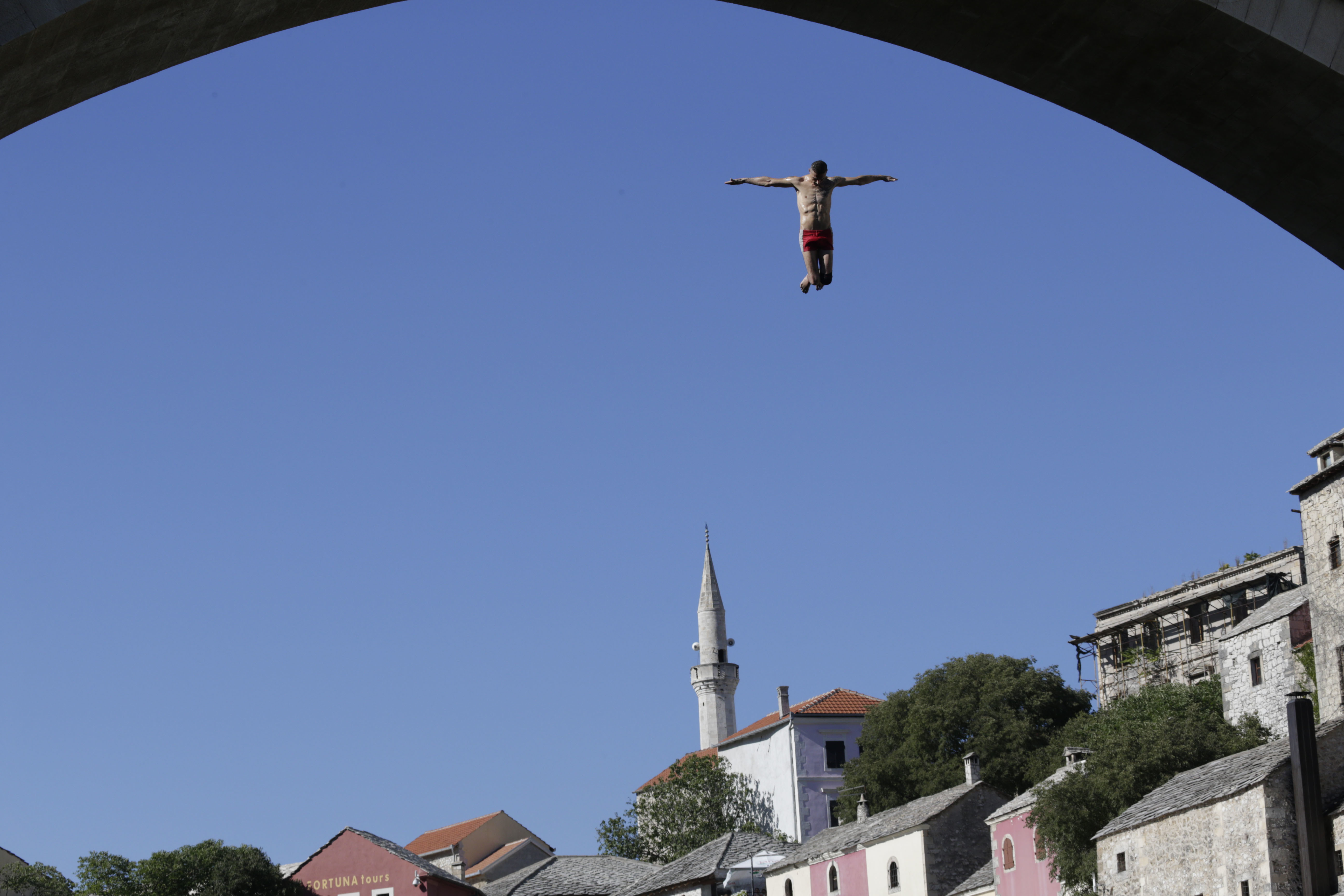 A diver drops through the air from the Mostar bridge during 451th traditional annual high diving competition, in Mostar, 140 kms south of Bosnian capital of Sarajevo, Sunday, July 30, 2017. Total of 41 divers from Bosnia and neighbouring countries competed diving from 25 meters high Old Mostar Bridge into the Neretva river. (AP Photo/Amel Emric)