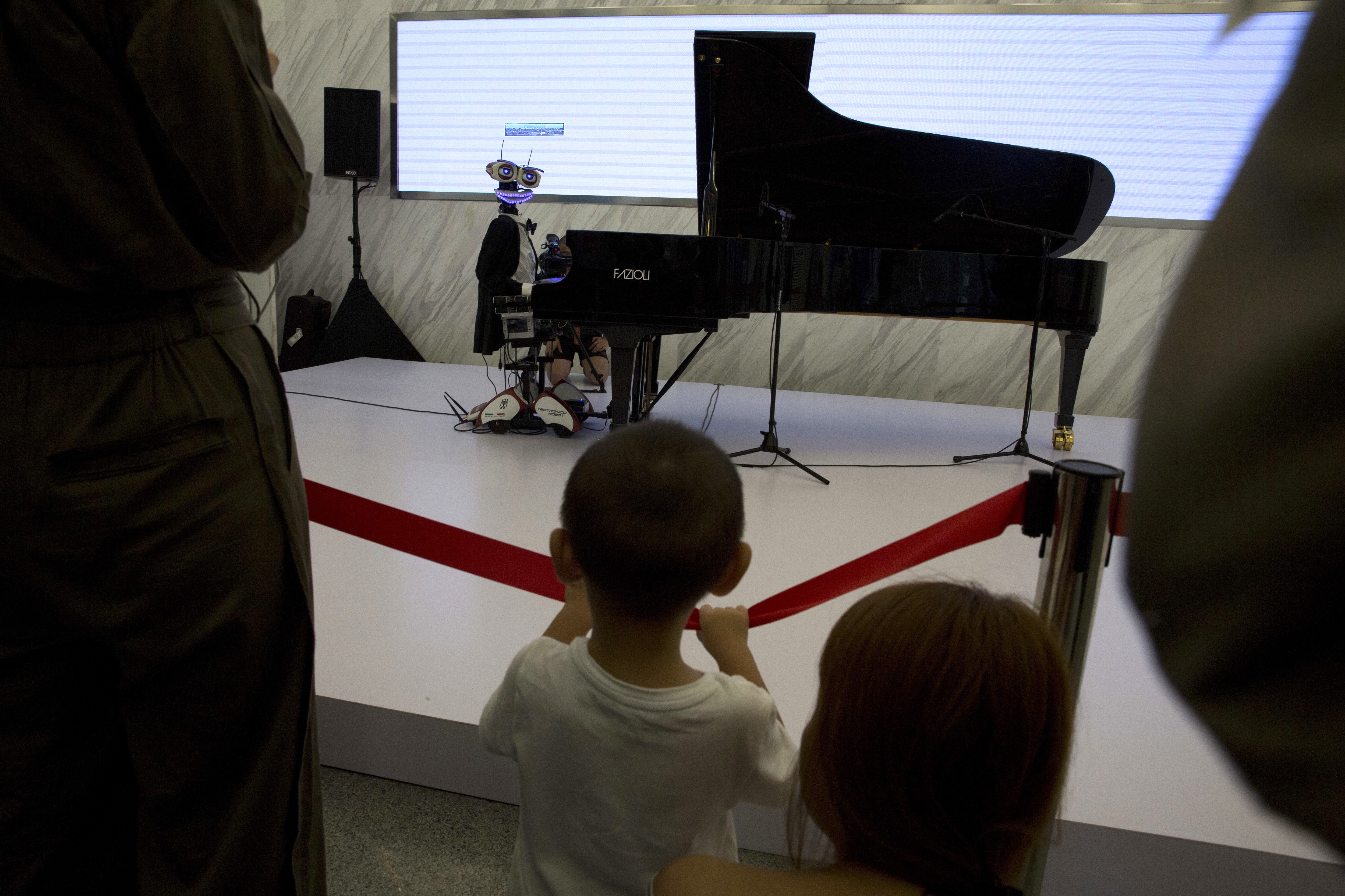 A child looks at a piano playing robot a day before the opening of the World Robot Conference held in Beijing, China, Tuesday, Aug. 22, 2017. The annual conference is a showcase of China's burgeoning robot industry ranging from companion robots to those deployed on manufacturing assembly line and entertainment. (AP Photo/Ng Han Guan)