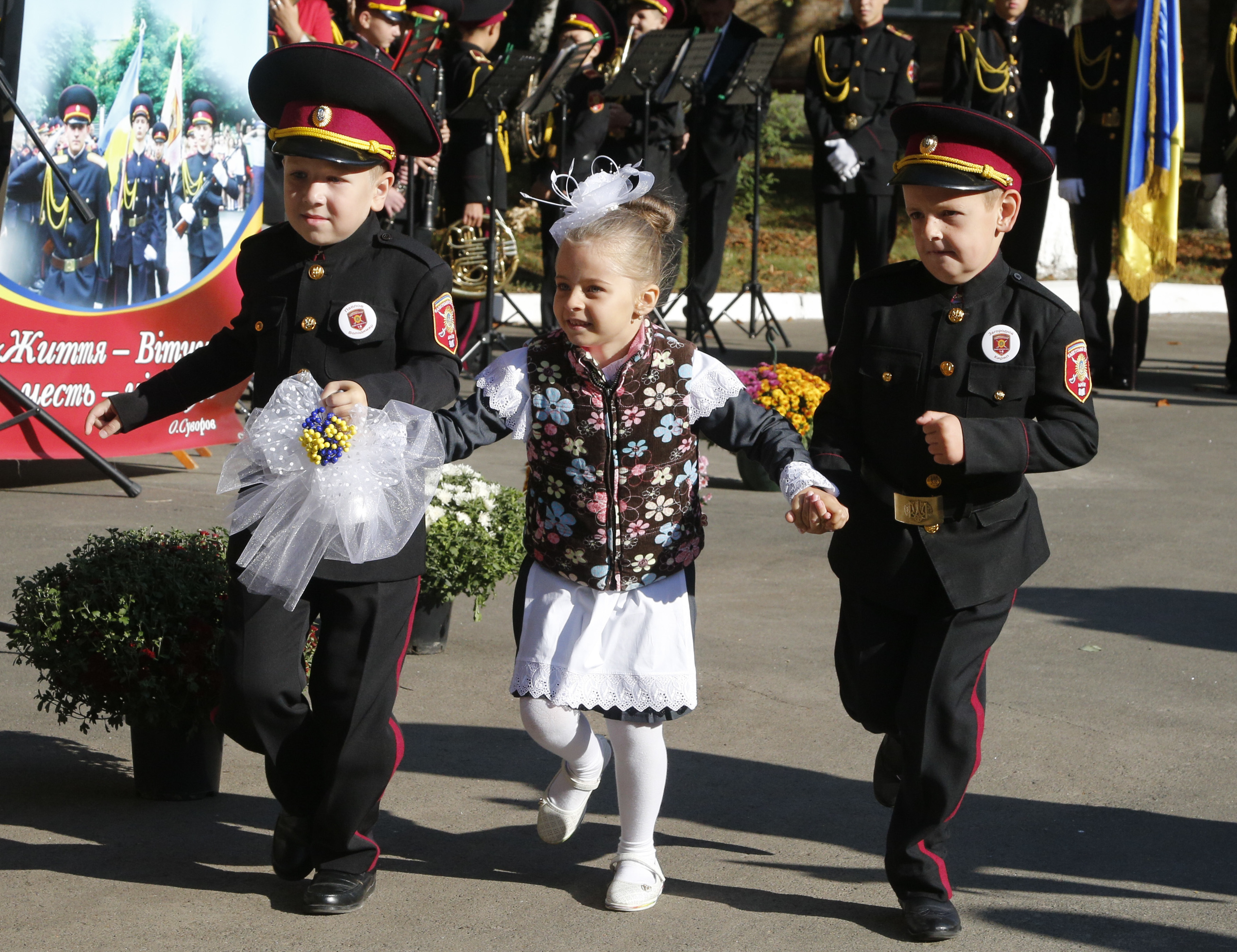 New cadets, a girl and two boys, run as they ring a symbolic bell at a ceremony on the occasion of the first day in school at a cadet lyceum in Kiev,Ukraine, Friday, Sept. 1, 2017. Ukraine marks Sept. 1 as Knowledge Day, as a traditional launch of the academic year. (AP Photo/Efrem Lukatsky)