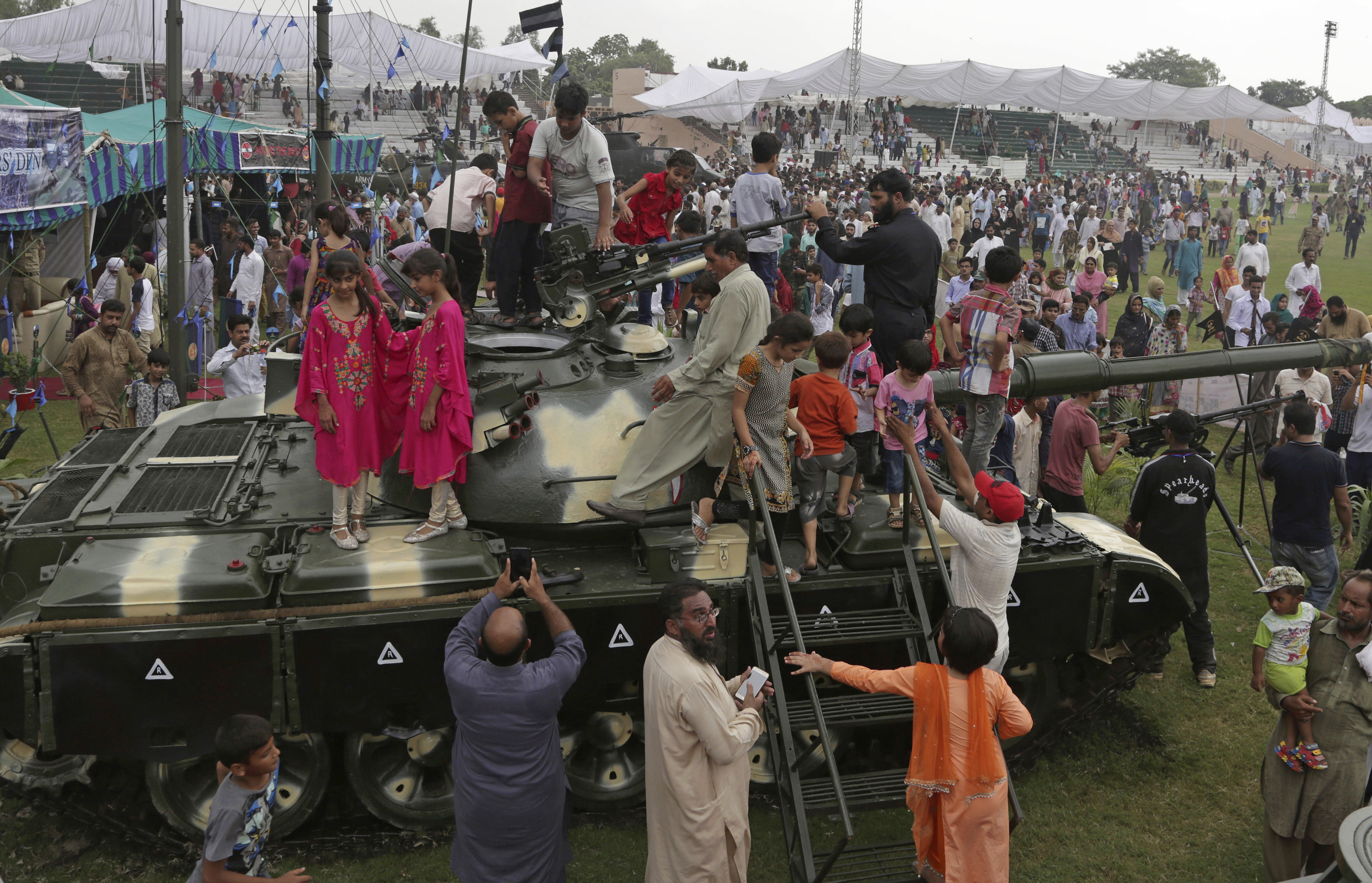 People climb on a tank at a military show to celebrate Pakistan Defense Day, marking the 1965 war with India over the disputed Kashmir region, in Lahore, Pakistan, Wednesday, Sept. 6, 2017. (AP Photo/K.M. Chaudary)