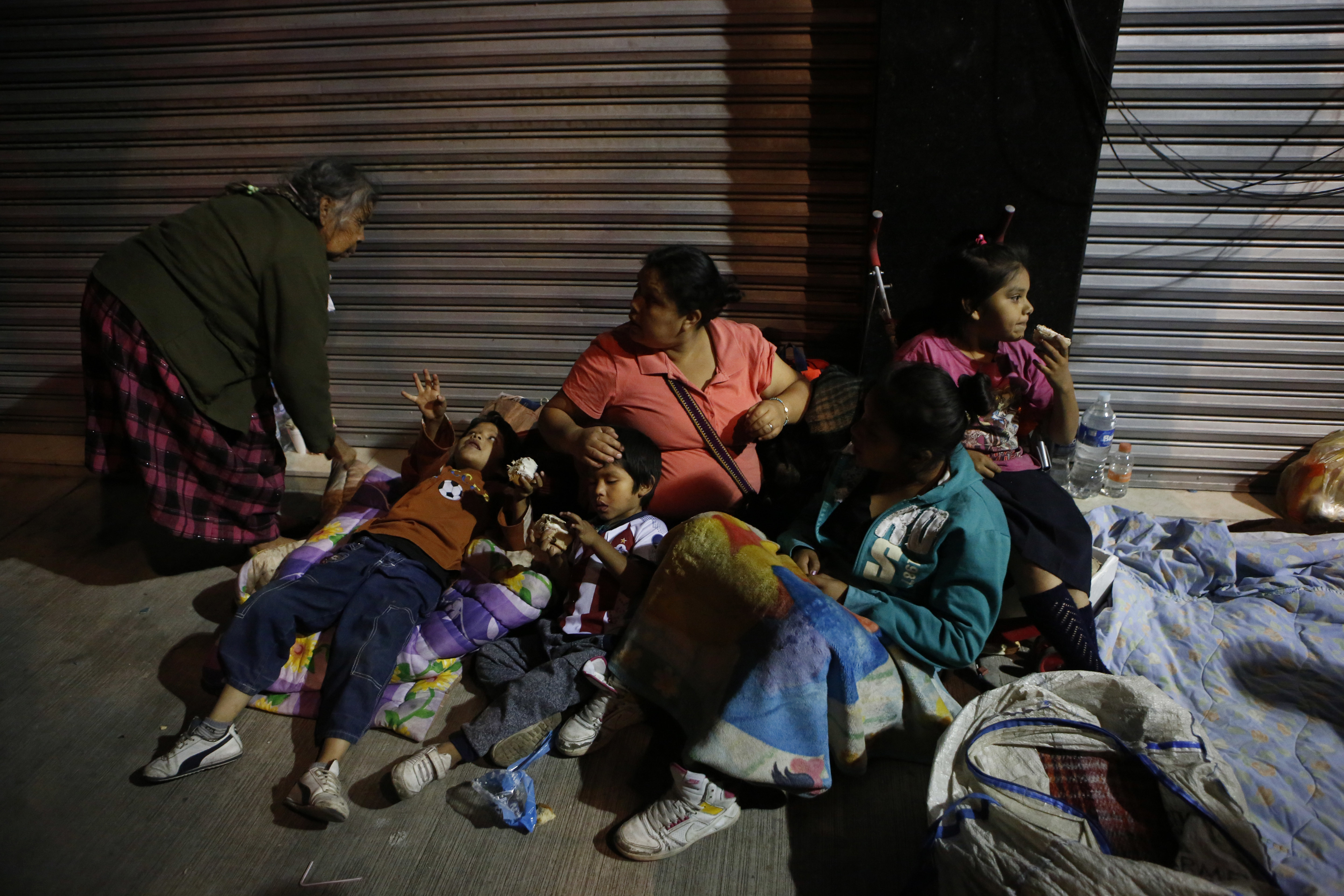 Families fearing aftershocks prepare to sleep on the street in the Roma neighborhood of Mexico City, Tuesday, Sept. 19, 2017. A magnitude 7.1 earthquake has stunned central Mexico, killing more than 100 people as buildings collapsed in plumes of dust. Thousands fled into the streets in panic, and many stayed to help rescue those trapped. (AP Photo/Rebecca Blackwell)