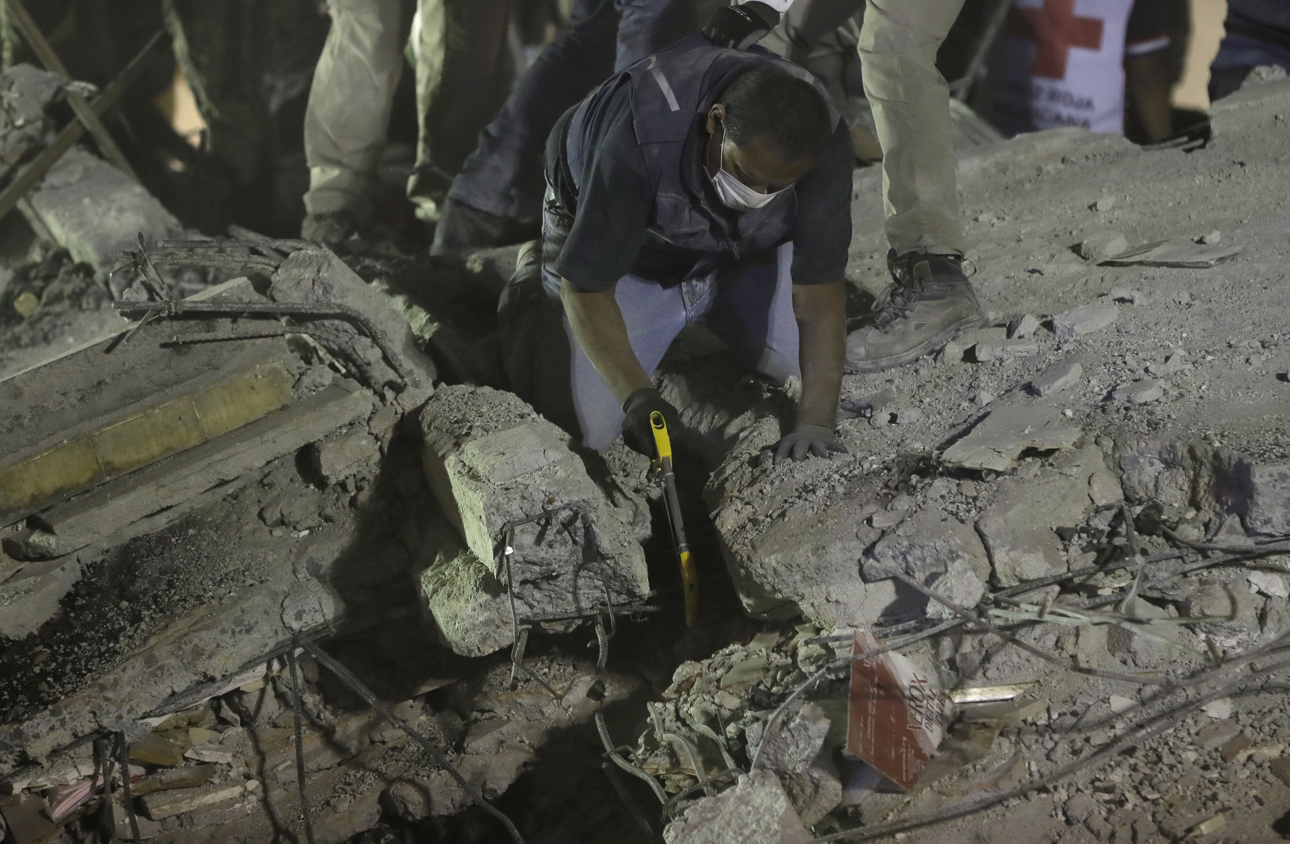 Rescue workers search for people trapped in a collapsed building in the Piedad Narvarte neighborhood of Mexico City, Tuesday, Sept. 19, 2017. A magnitude 7.1 earthquake has stunned central Mexico, killing more than 100 people as buildings collapsed in plumes of dust. Thousands fled into the streets in panic, and many stayed to help rescue those trapped. (AP Photo/Rebecca Blackwell)