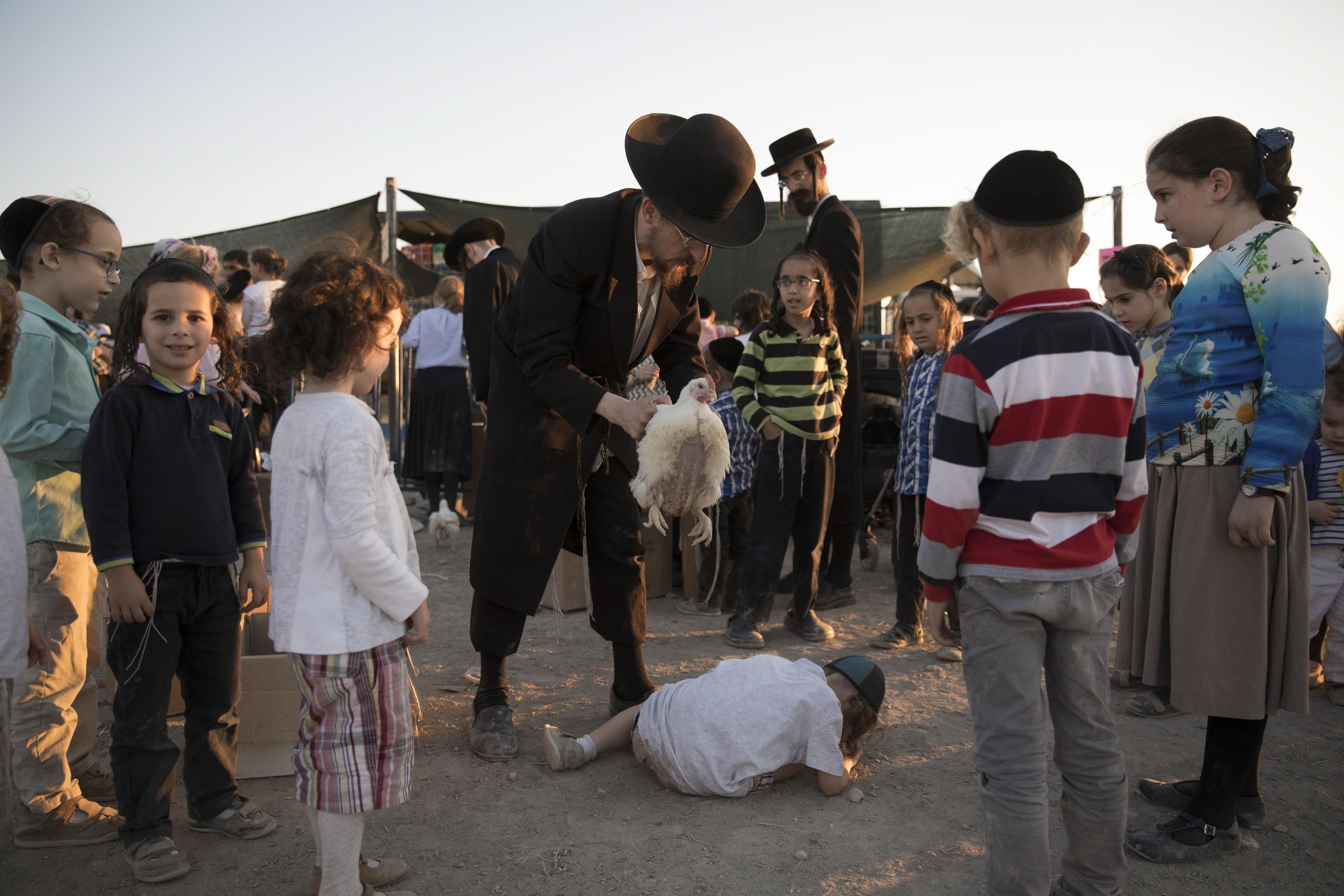 epa06233004 An ultra-Orthodox Jews performs a Jewish ritual called 'Kaparot,' performed before Yom Kippur, the Day of Atonement and the holiest of Jewish holidays, in Beit Shemesh, Israel, 28 September 2017. The Kaparot is a blessing and prayer recited as a live fowl, or chicken is passed over a person's head, symbolically transferring that person's sins accumulated over the past year into the bird, which is butchered and eaten or donated to charity. Yom Kippur begins at sundown on 29 September when the entire country comes to a standstill as people fast and spend much of the day in prayer.  EPA/ABIR SULTAN