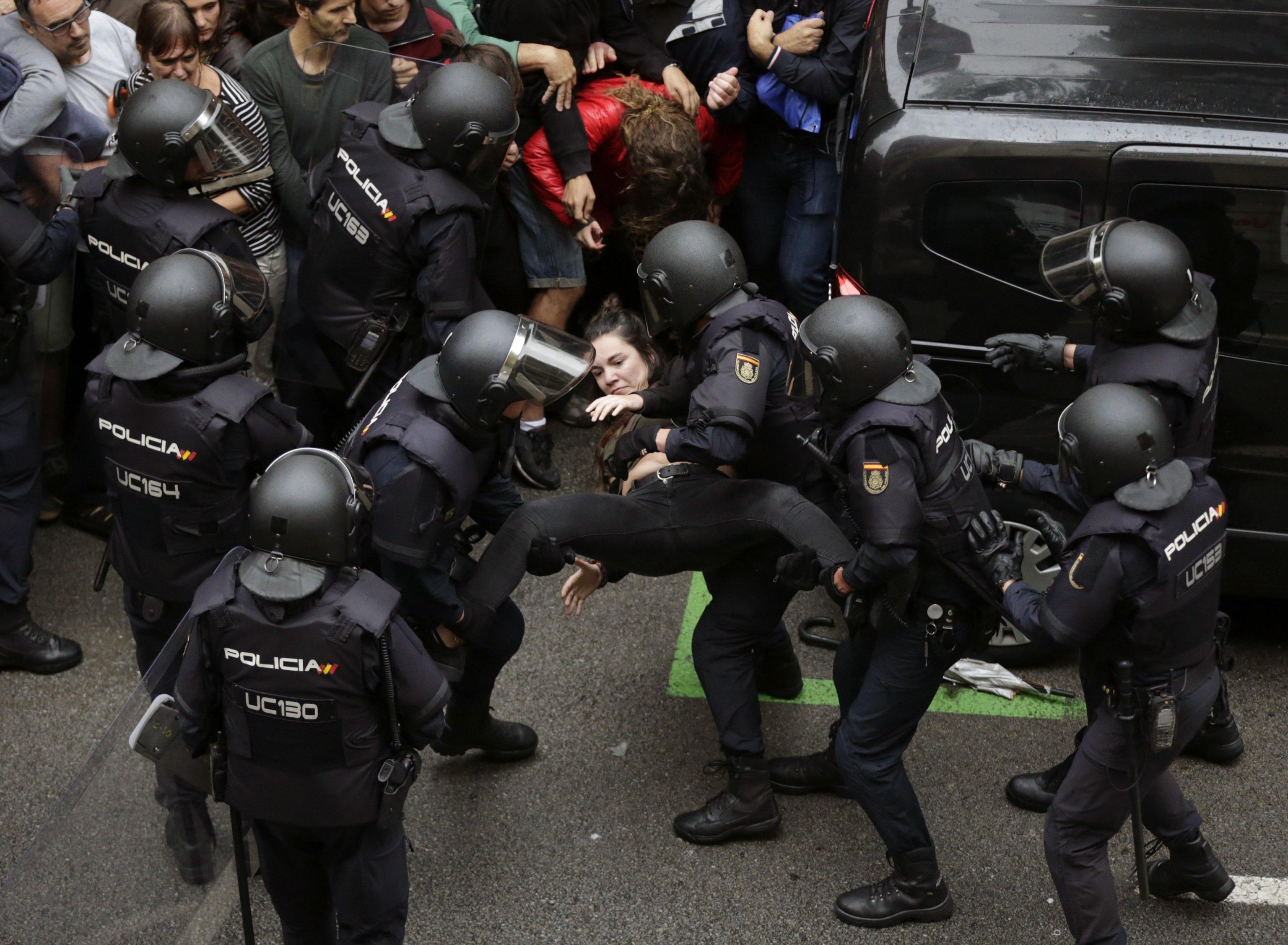 Spanish National riot policemen evict a young woman during clashes between the people gathered outside the Ramon Llull school and police forces during the '1-O Referendum' in Barcelona, Catalonia, on 01 October 2017. National Police officers and Civil guards have been deployed in Barcelona to prevent the people from entering to the polling centers and vote in the Catalan independence referendum, that has been banned by the Spanish Constitutional Court. The police action has provocked clashes between pro-independence people and the police forces.  EPA/Alberto Estevez