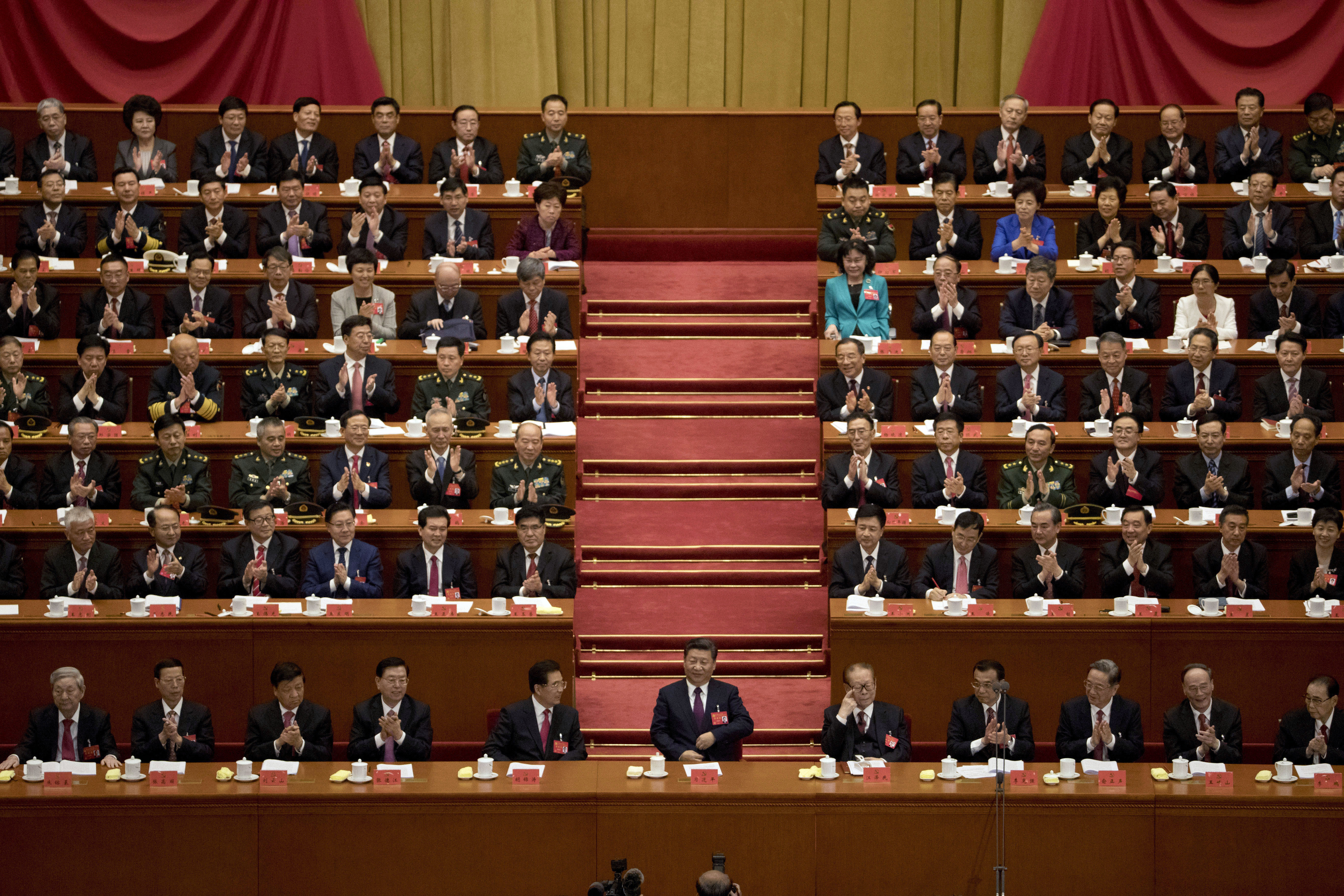 Chinese President Xi Jinping, center, sits with former Chinese President Hu Jintao, fifth left, and Jiang Zemin, fifth right, after delivering his speech at the opening ceremony of the 19th Party Congress held at the Great Hall of the People in Beijing, China, Wednesday, Oct. 18, 2017. Xi on Wednesday urged a reinvigorated Communist Party to take on a more forceful role in society and economic development to better address 