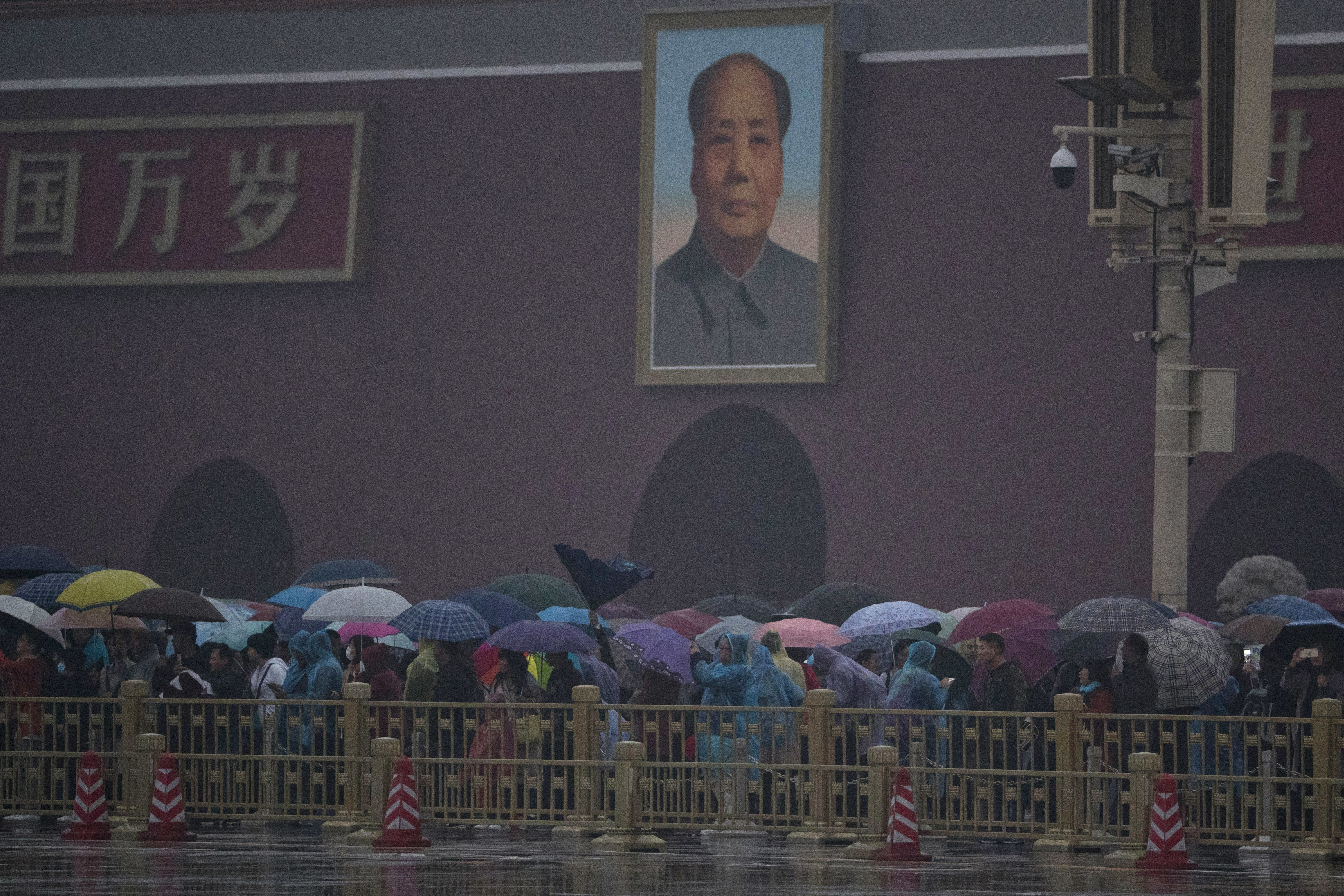 Tourists gather near the portrait of Mao Zedong to watch the flag raising ceremony on the day of the 19th Party Congress in Beijing, China, Wednesday, Oct. 18, 2017. Chinese President Xi Jinping on Wednesday urged a reinvigorated Communist Party to take on a more forceful role in society and economic development to better address 