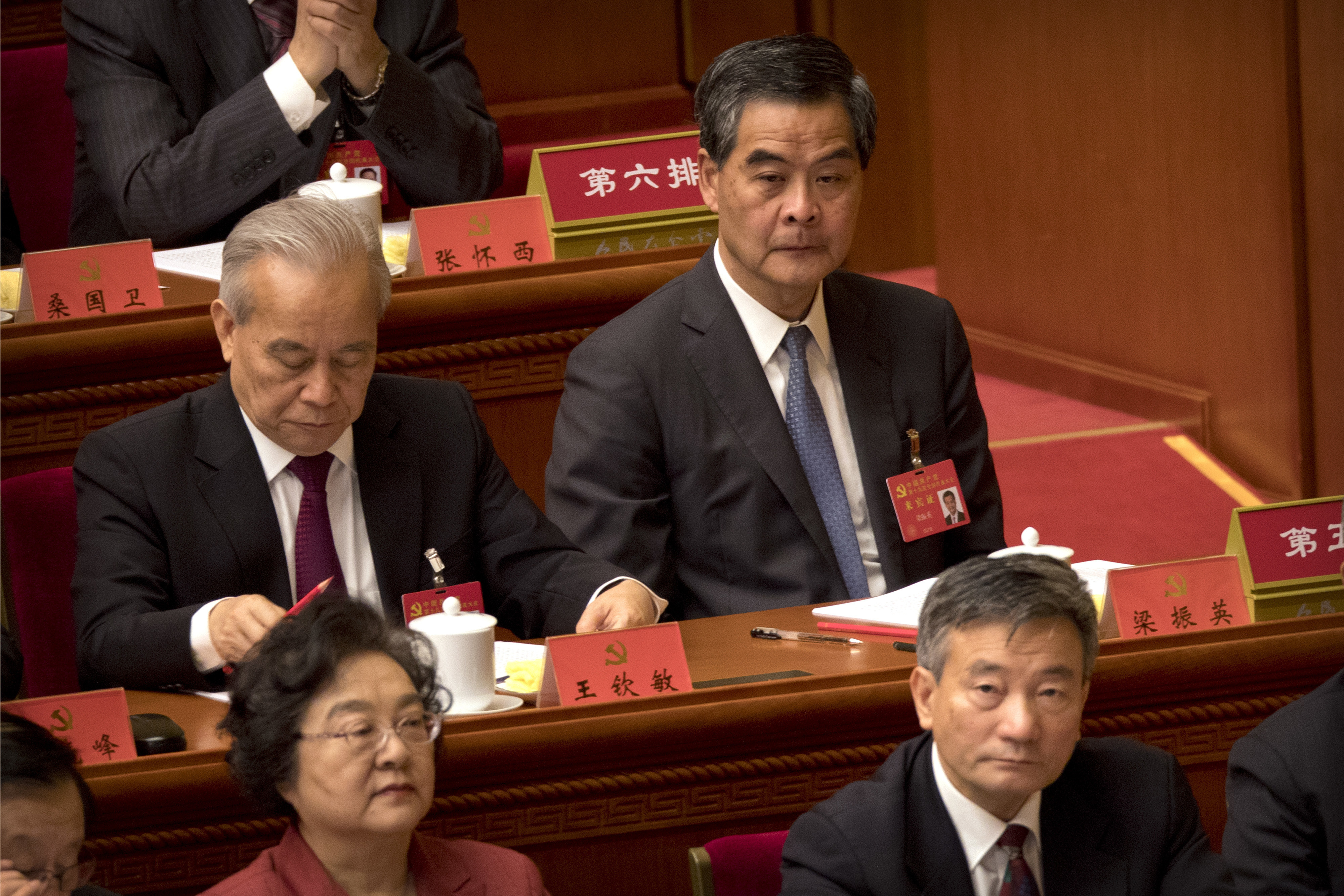 Former Hong Kong Executive Leung Chun-ying, rear right, listens to a speech by Chinese President Xi Jinping during the opening session of China's 19th Party Congress at the Great Hall of the People in Beijing, Wednesday, Oct. 18, 2017. Xi on Wednesday urged a reinvigorated Communist Party to take on a more forceful role in society and economic development to better address 