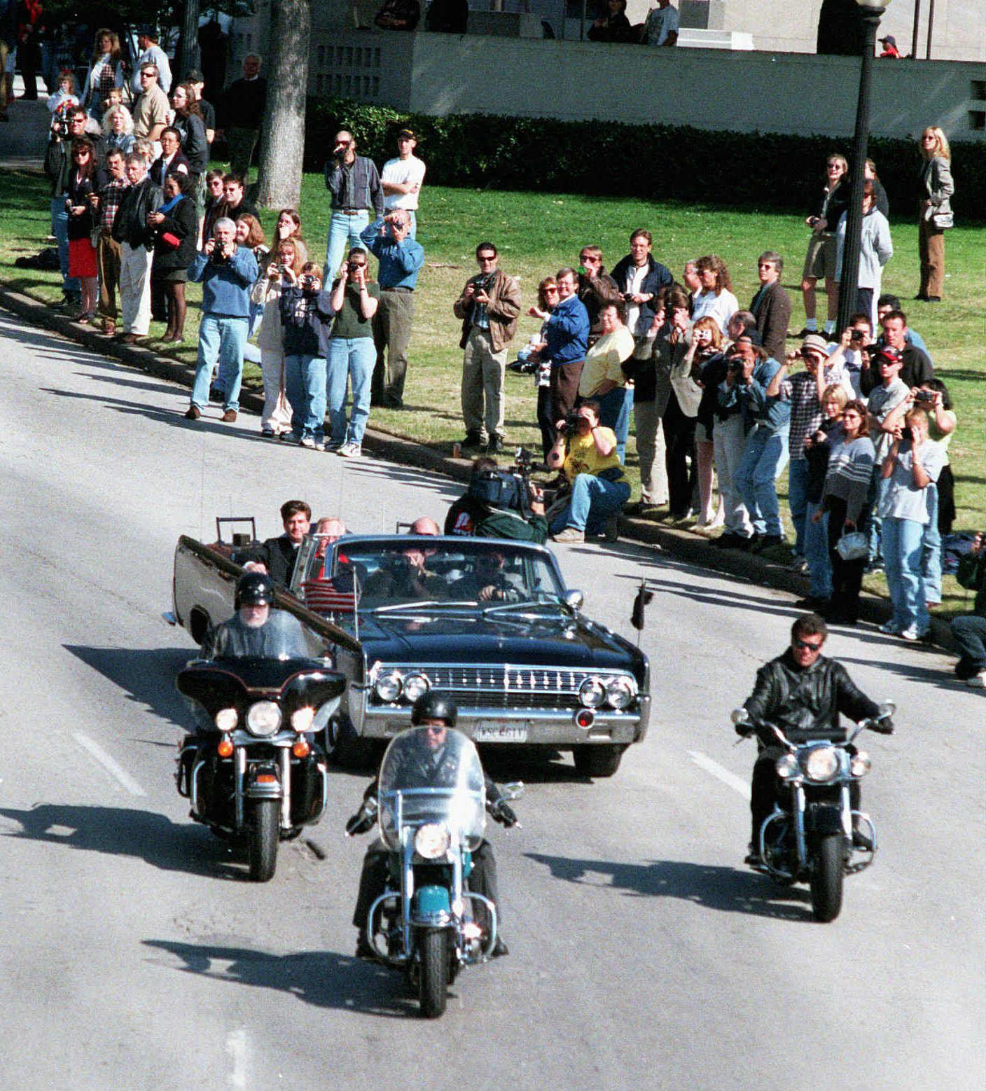 Onlookers line the street as a re-creation of the motorcade of President John F. Kennedy drives through Dealey Plaza in downtown Dallas on the anniversary of the 1963 assasination of Kennedy, Saturday, Nov. 22, 1997. (AP Photo/Dallas Morning News, Lisa LeVrier)