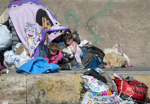 Bambini con la mamma in Grecia accampati con altri migranti foto Ap