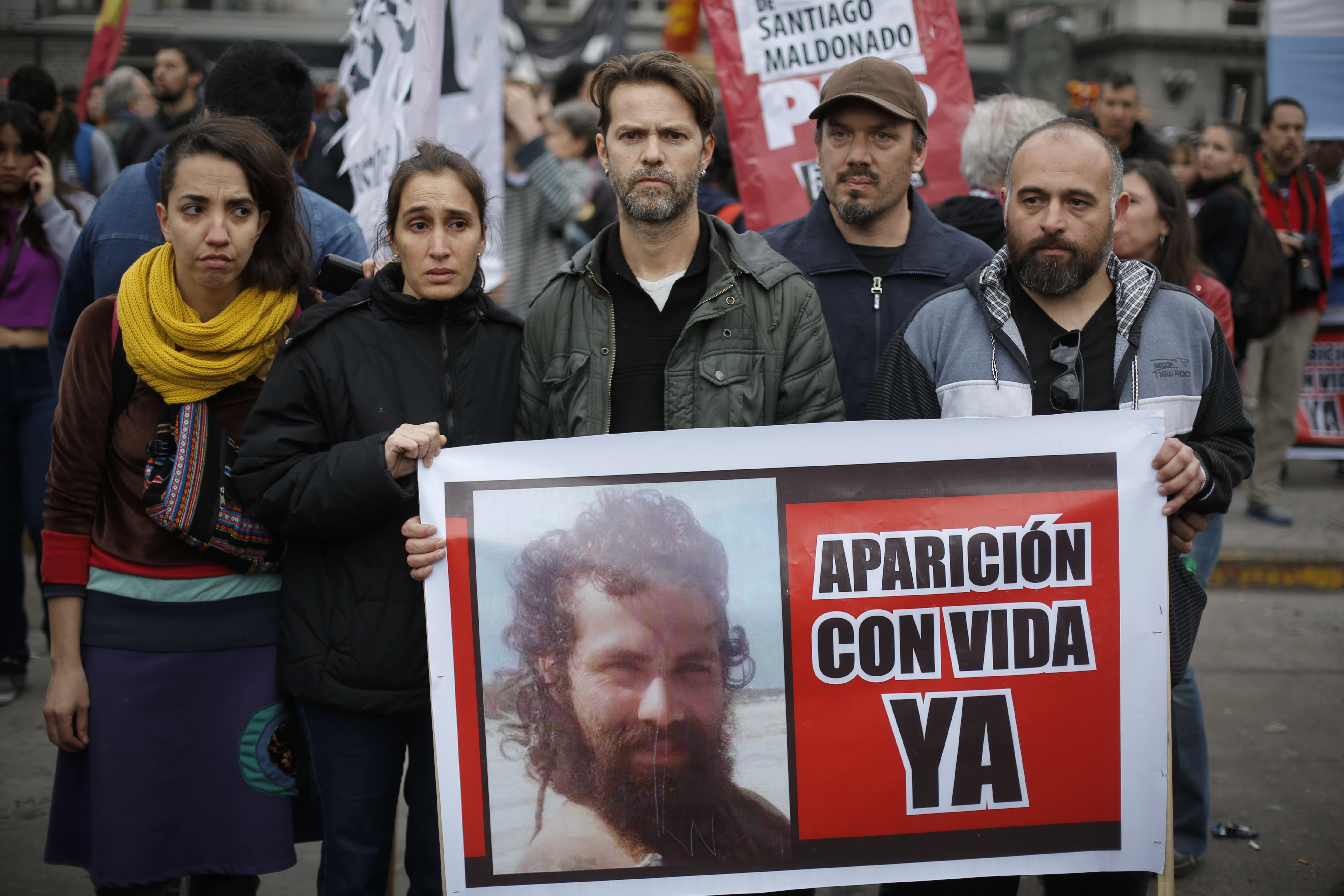 Relatives of Santiago Maldonado, including his brother German, center, and activists, hold photos of Maldonado and the Spanish message 