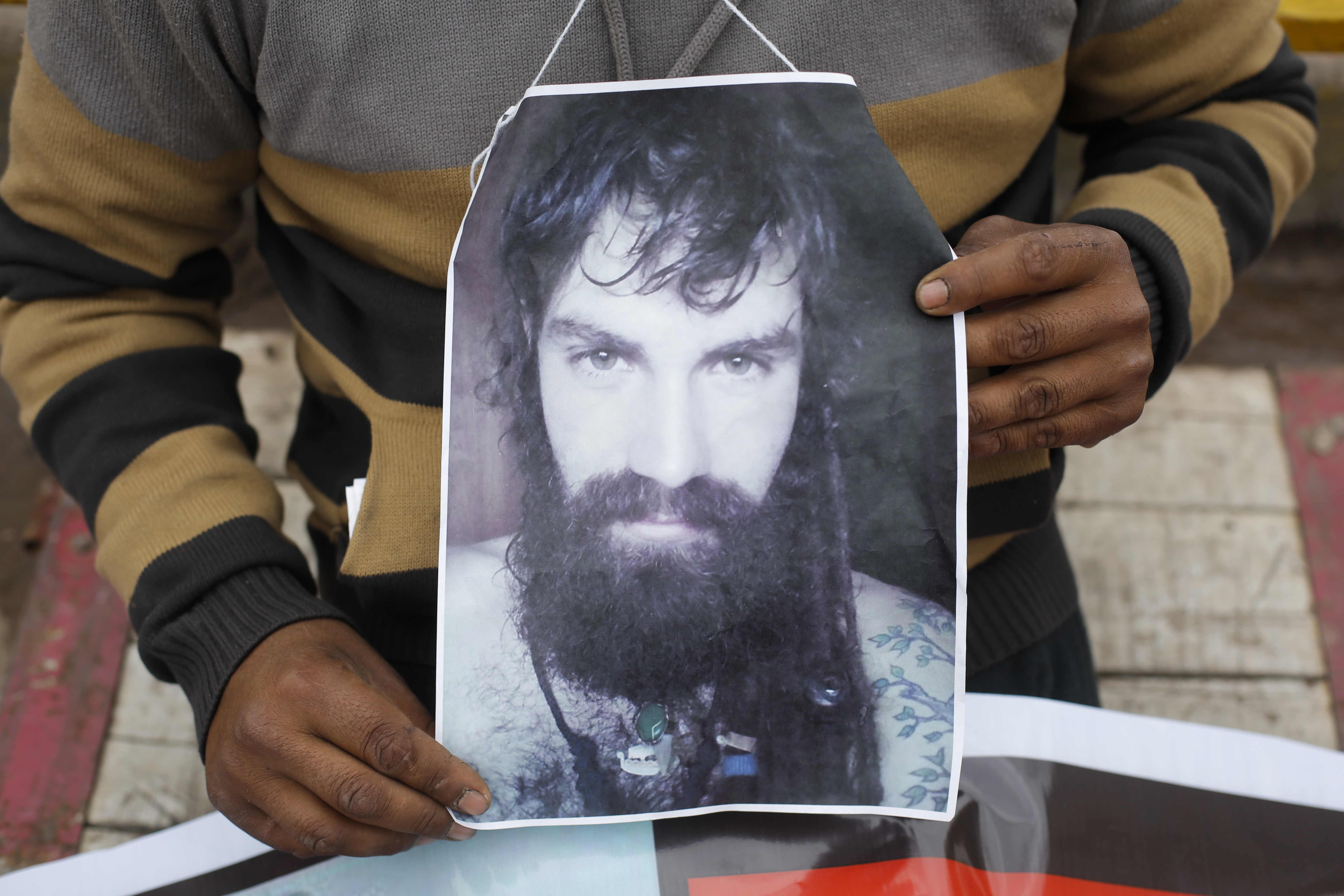 An activist holds a photo of Santiago Maldonado during a protest against his disappearance, outside Congress in Buenos Aires, Argentina, Monday, Aug. 7, 2017. Santiago Maldonado's family says Argentine border police captured him on Aug. 1 during an operative to move Mapuche indigenous off land they have occupied since 2015, which the Mapuche claim is their ancestral land. The land in question is owned by Italian clothing group Benetton in Argentina's Patagonia, according to Diego Campal, spokesperson for 