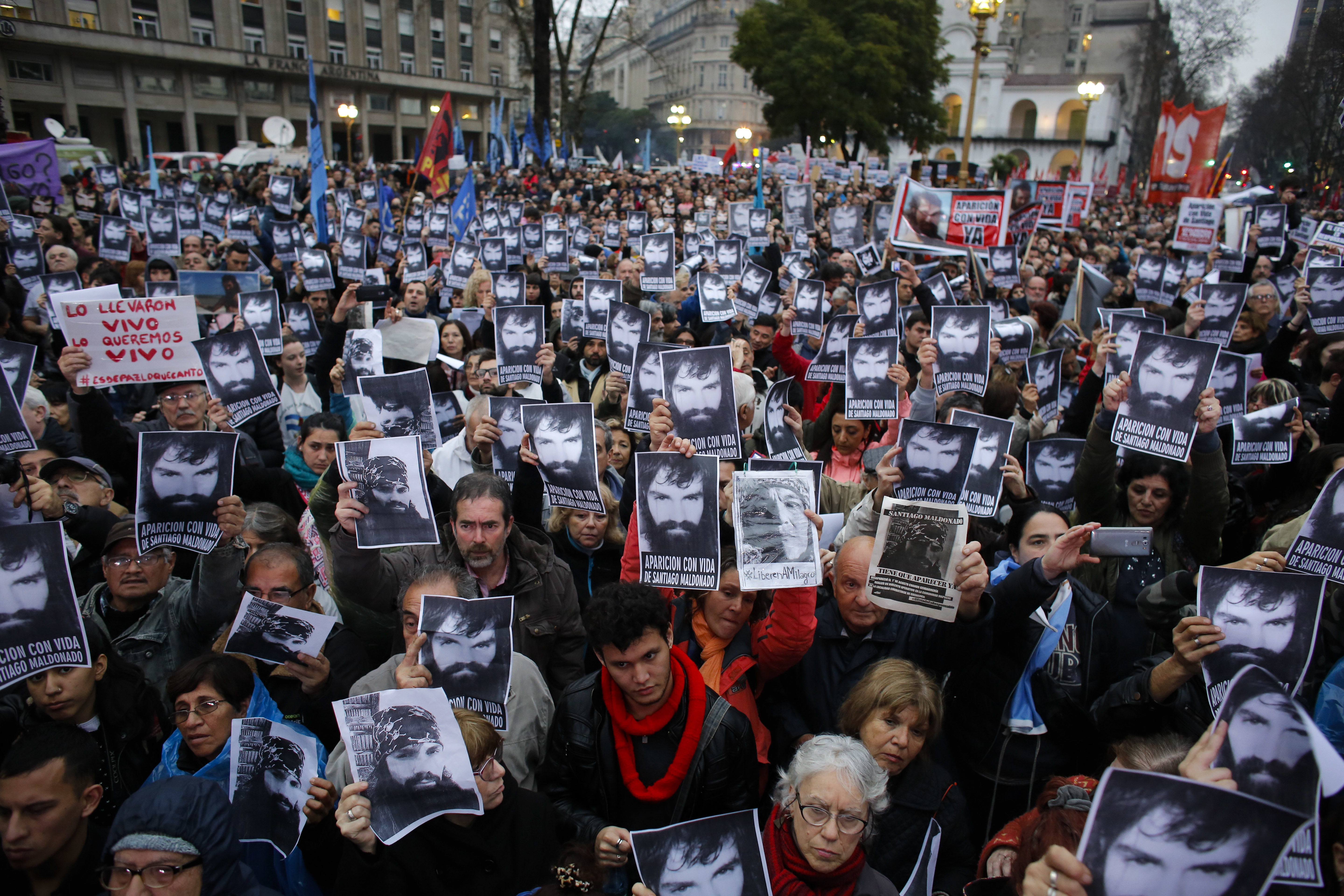 People hold photos of Santiago Maldonado, who's missing, during a demonstration at Plaza de Mayo in Buenos Aires, Argentina, Friday, Aug. 11, 2017. Human rights groups say Maldonado went missing after Argentine border police captured him on Aug. 1 during an operative against Mapuche indigenous who were blocking a highway in Argentina's Patagonia. (AP Photo/Victor R. Caivano)