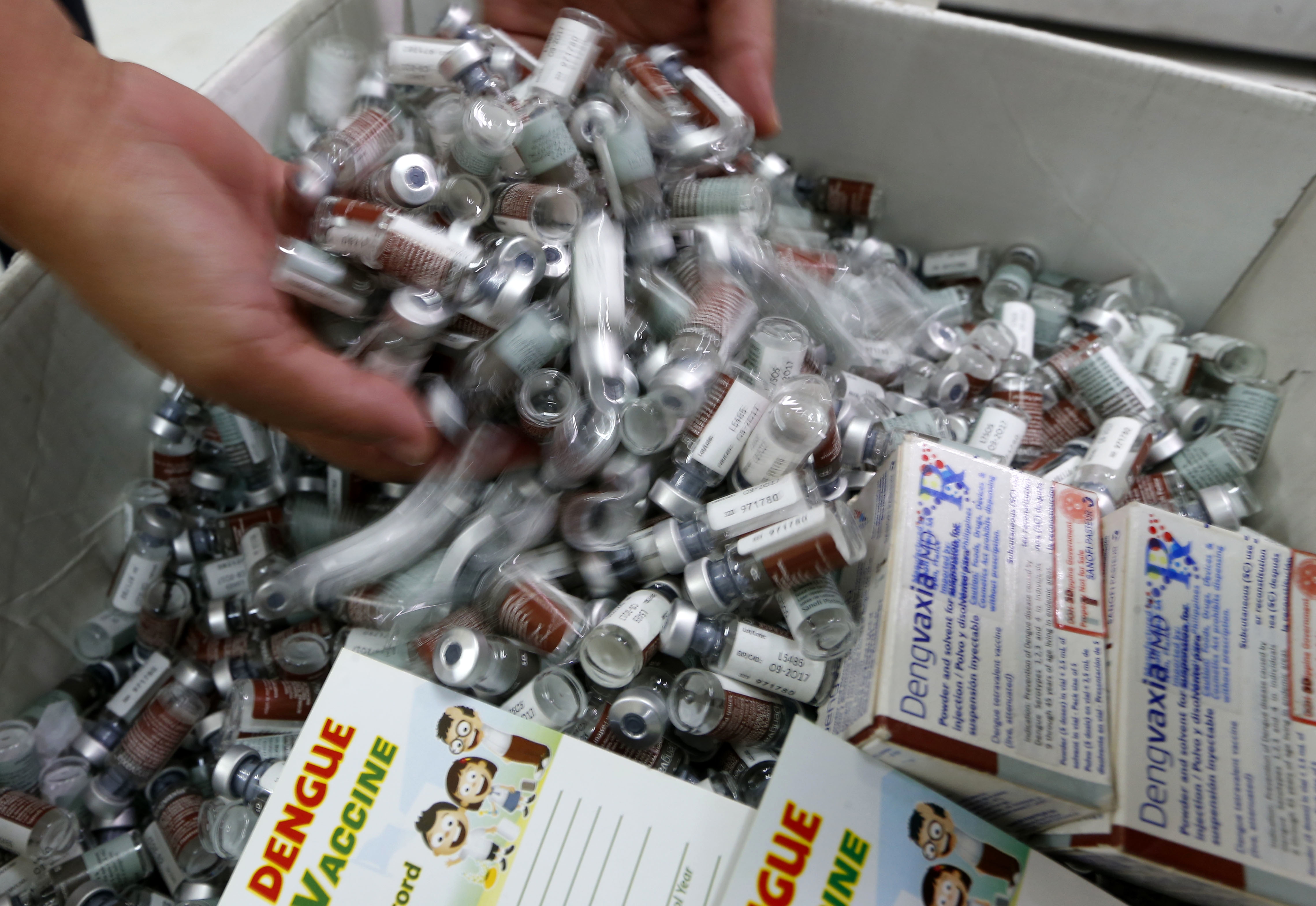 A Manila Health offricer scoops empty vials of the anti-dengue vaccine Dengvaxia inside the vaccine storage room Tuesday, Dec. 5, 2017 in Manila, Philippines. The controversial vaccine, manufactured by Sanofi Pasteur and administered to more than 700,000 Filipino children, was put on hold by the Philippines last week after new study findings showed it posed risks of severe cases in people without previous infection. The drug was recalled Tuesday from local health centers following the controversy. (AP Photo/Bullit Marquez)