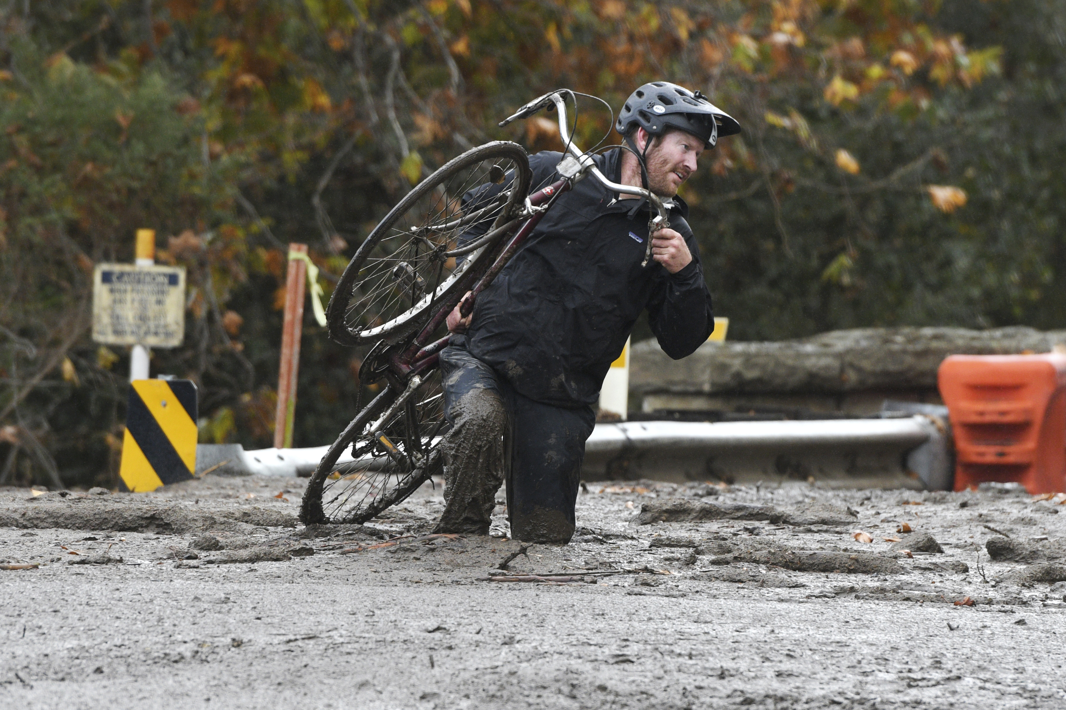 Carpinteria resident Jeff Gallup carries his bike through mud on Foothill Road in Carpinteria, Calif., Tuesday, Jan. 9, 2018. Homes were swept from their foundations as heavy rain sent mud and boulders sliding down hills stripped of vegetation by Southern California's recent wildfires. (AP Photo/Michael Owen Baker)