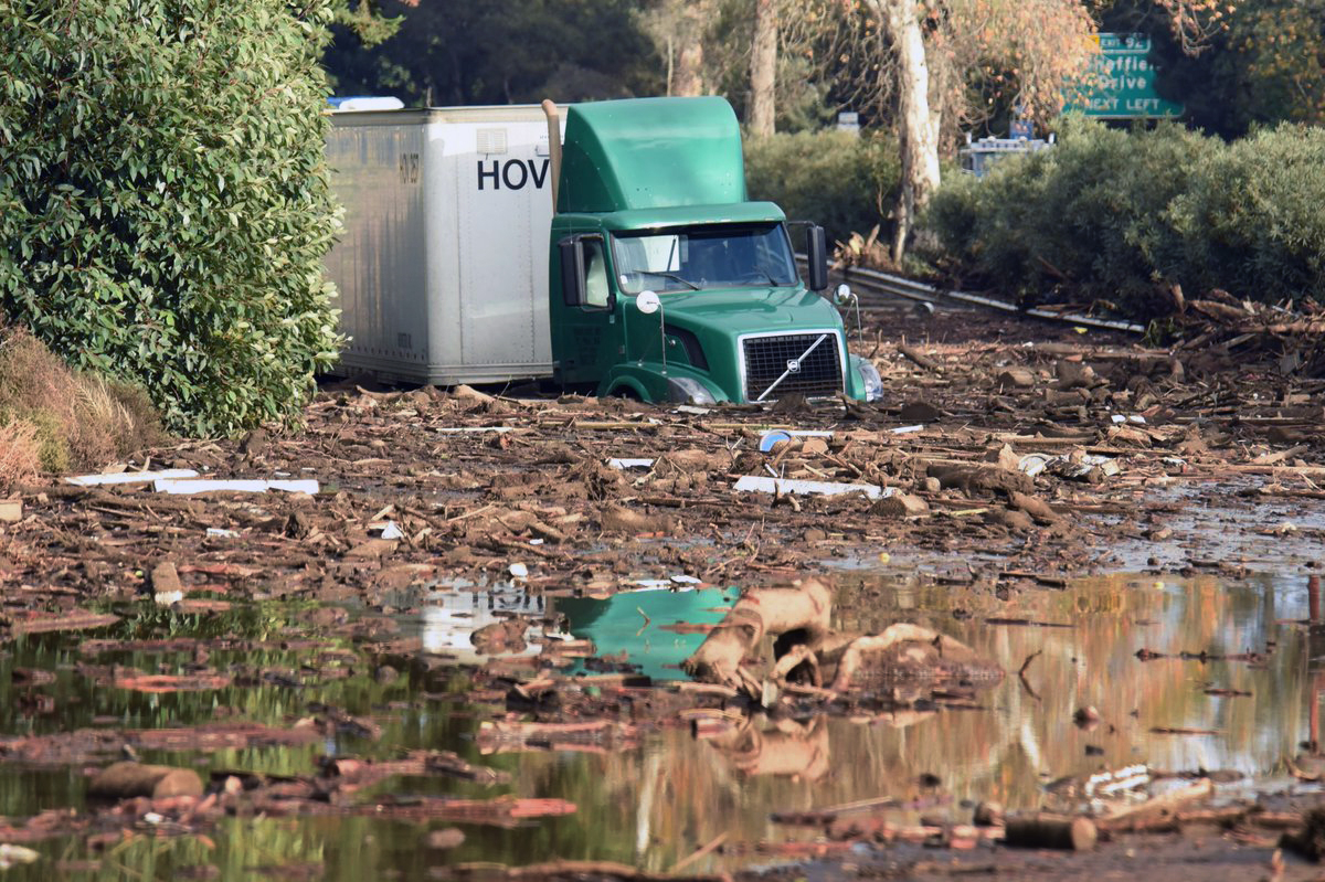 In this photo provided by the Santa Barbara County Fire Department, shows a semi-tractor trailer sits stuck in mud on U.S. Highway 101, in Montecito, Calif. on Tuesday, Jan. 9, 2018. Homes were swept away before dawn Tuesday when mud and debris roared into neighborhoods in Montecito from hillsides stripped of vegetation during a recent wildfire. (Mike Eliason/Santa Barbara County Fire Department via AP)