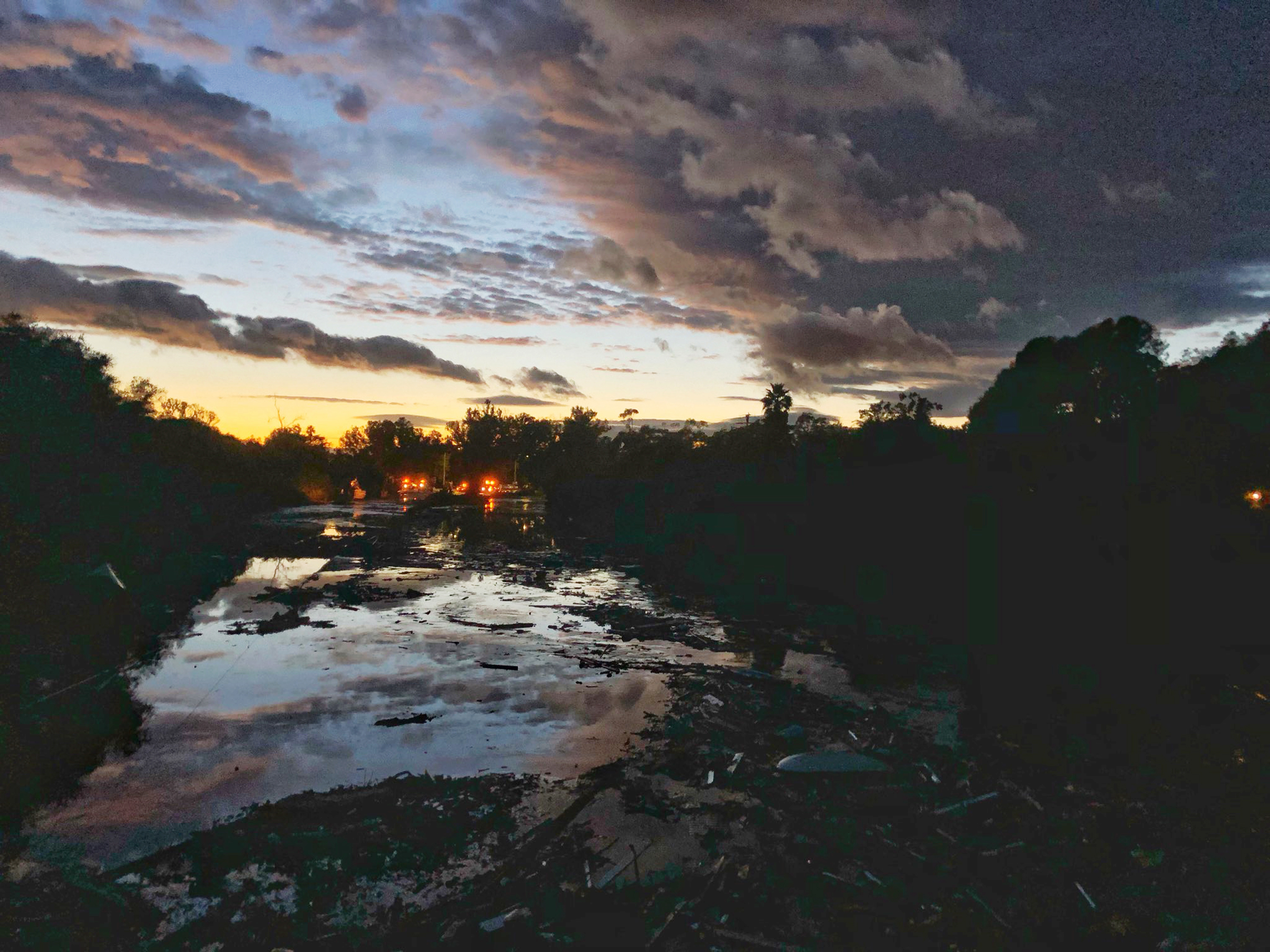 This photo provided by the Santa Barbara County Fire Department shows the sun setting over the flooded US 101 Freeway at Olive Mill Road, which remains flooded with runoff water from Montecito Creek in Montecito, Calif., Tuesday, Jan. 9, 2018. Several homes were swept away before dawn Tuesday when mud and debris roared into neighborhoods in Montecito from hillsides stripped of vegetation during the Thomas wildfire. (Mike Eliason/Santa Barbara County Fire Department via AP)