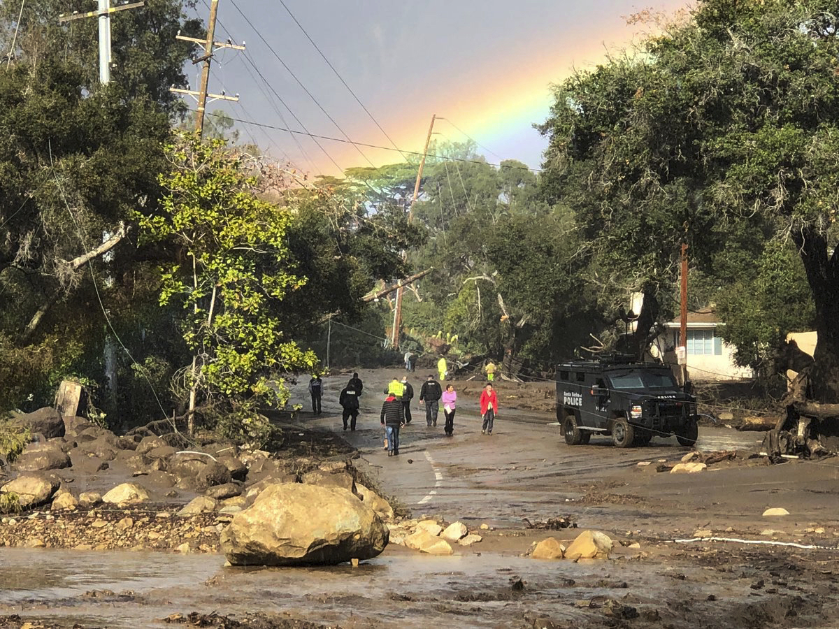 In this photo provided by Santa Barbara County Fire Department, shows a rainbow forming above Montecito, Calif. while law enforcement and the curious survey the destruction on Hot Springs Road on Tuesday, Jan. 9, 2018. Homes were swept away before dawn Tuesday when mud and debris roared into neighborhoods in Montecito from hillsides stripped of vegetation during a recent wildfire. (Mike Eliason/Santa Barbara County Fire Department via AP)