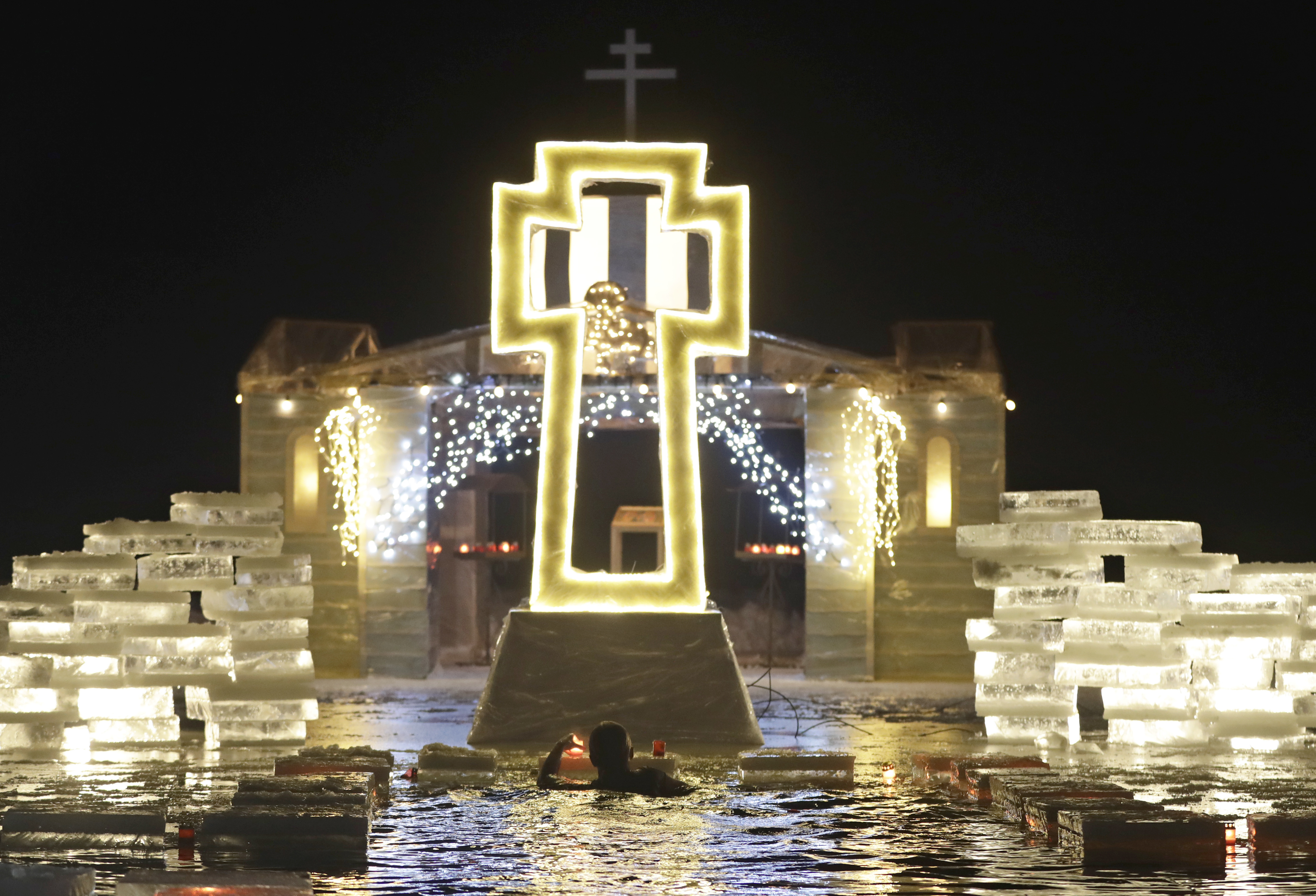 A man puts a candle while bathing in the ice cold water after plunging into it during Orthodox Epiphany celebrations at a lake in the village of Lysaya Gora, north of capital Minsk, Belarus, early Friday, Jan. 19, 2018. Thousands of Belarusian Orthodox Church followers plunged into icy rivers and ponds across the country to mark Epiphany, cleansing themselves with water deemed holy for the day. (AP Photo/Sergei Grits)