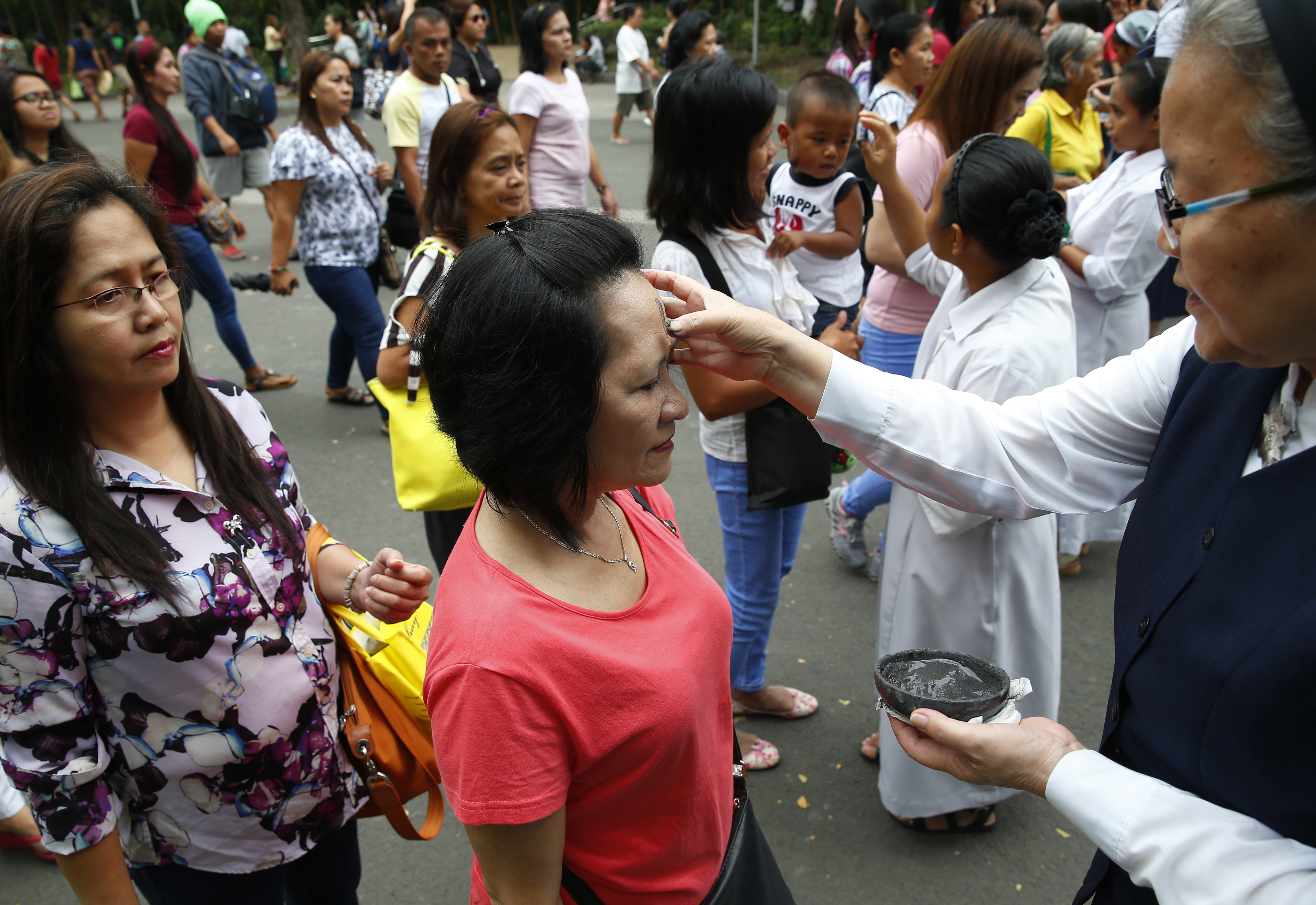 Roman Catholic devotees have their foreheads rubbed with ash in observance of Ash Wednesday which ushers the season of Lent and also coincides with Valentine's Day celebration Wednesday, Feb. 14, 2018, in Paranaque southeast of Manila, Philippines. Ash Wednesday is observed all over the world by Roman Catholics to remind mankind that God created humans from dust. (AP Photo/Bullit Marquez)
