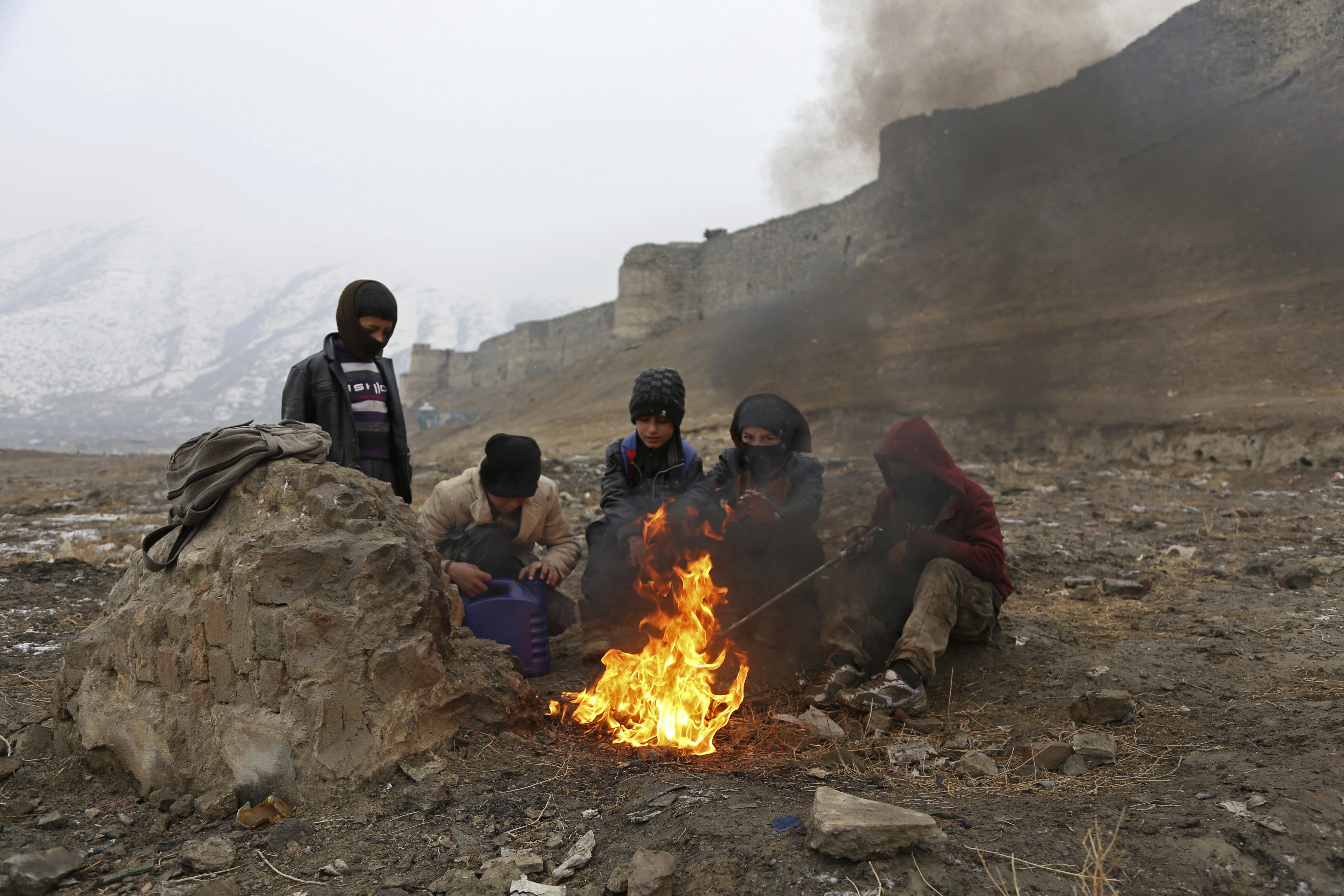Boys warm themselves near a fire during a rainy day, on the outskirts of Kabul, Afghanistan, Wednesday, Jan. 31, 2018. (AP Photo/Rahmat Gul)